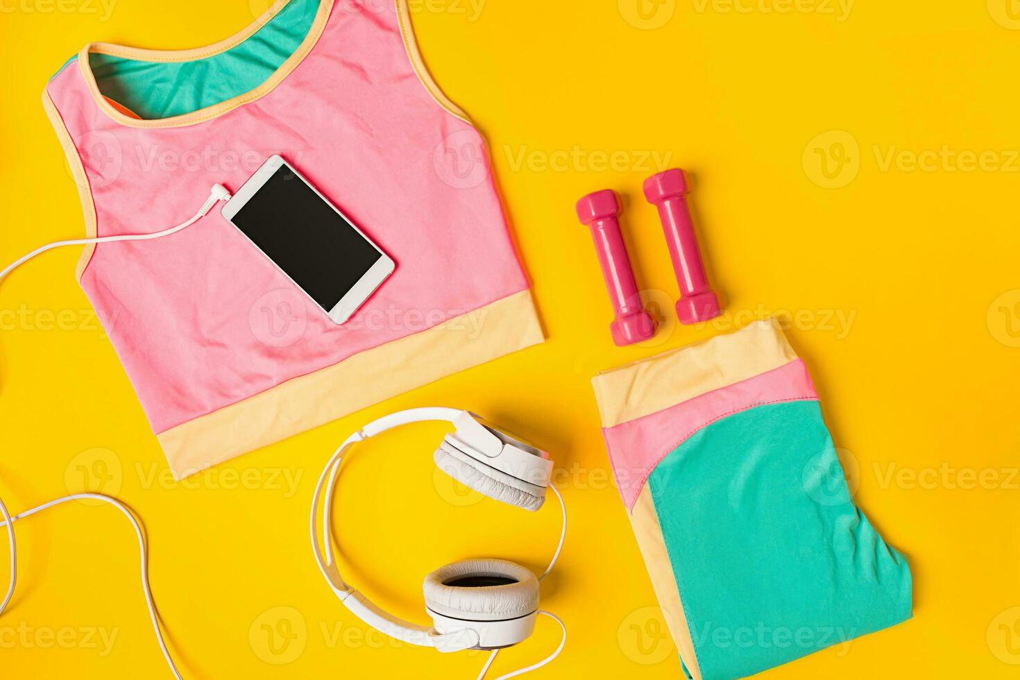 Sport equipment and clothes with mobile phone on yellow background. Top view photo