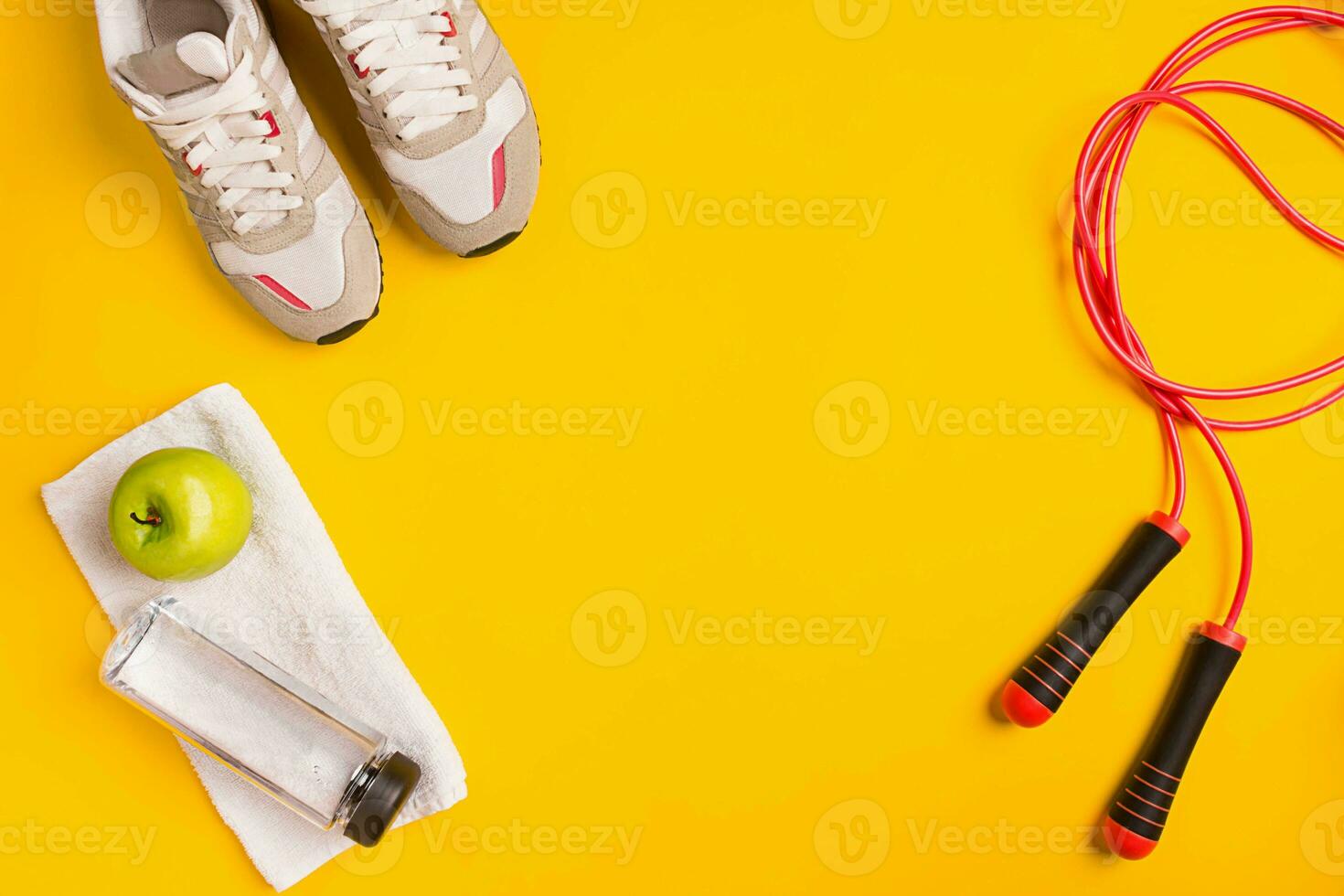 Athlete's set with female clothing, skipping rope and bottle of water on yellow background photo