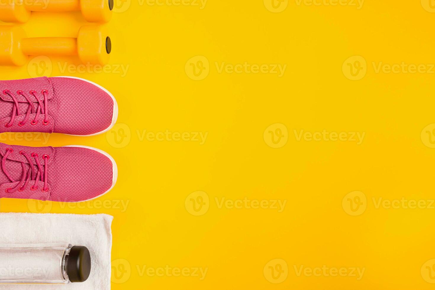 Athlete's set with female clothing, dumbbells and bottle of water on yellow background photo