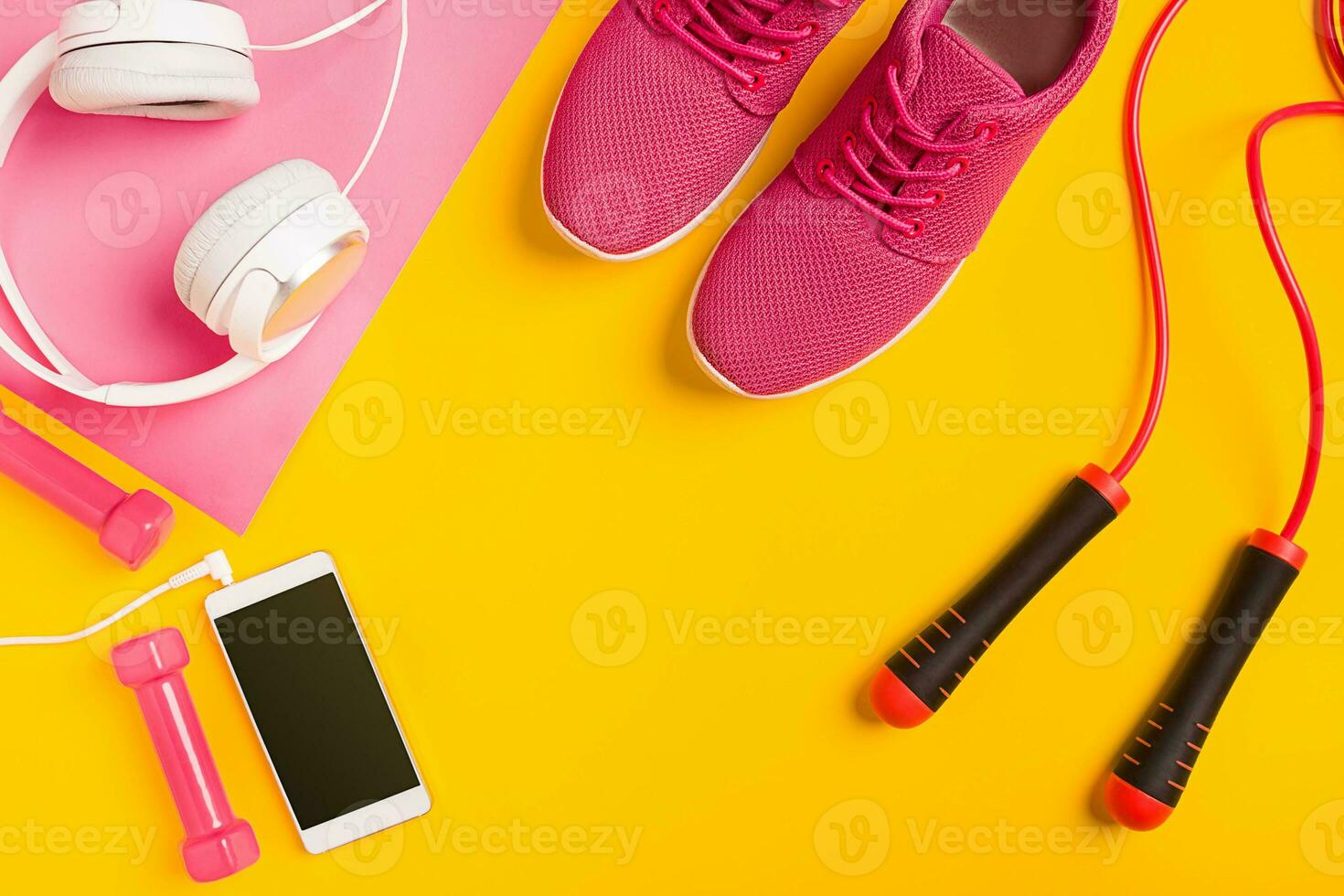 Fitness accessories on yellow background. Sneakers, dumbbells, headphones and smart. photo