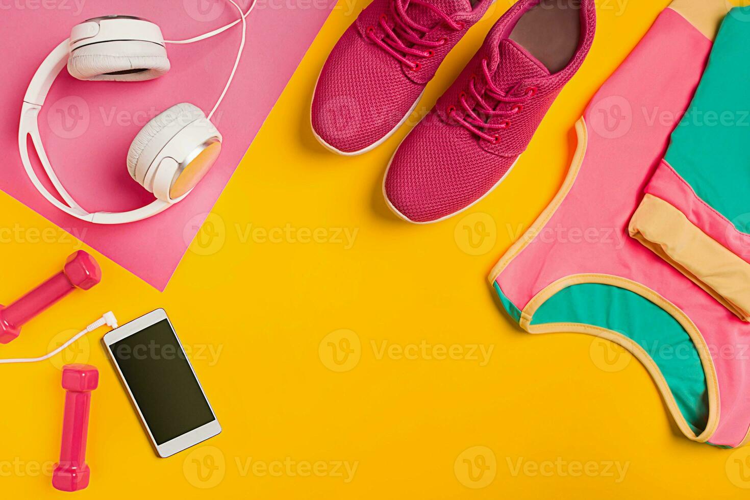 Athlete's set with female clothing, dumbbells and bottle of water on yellow background photo