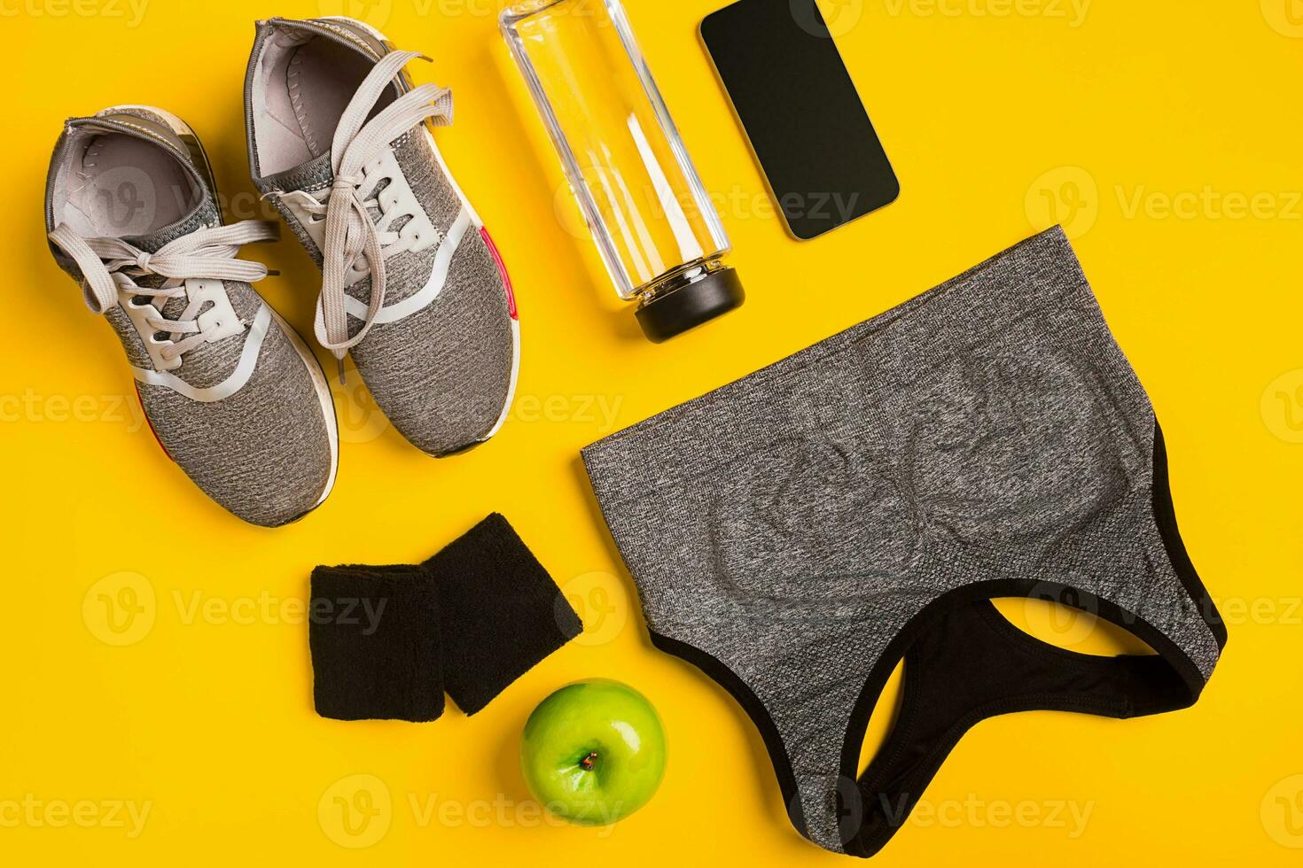 Fitness accessories on a yellow background. Sneakers, bottle of water, smart and sport top. photo