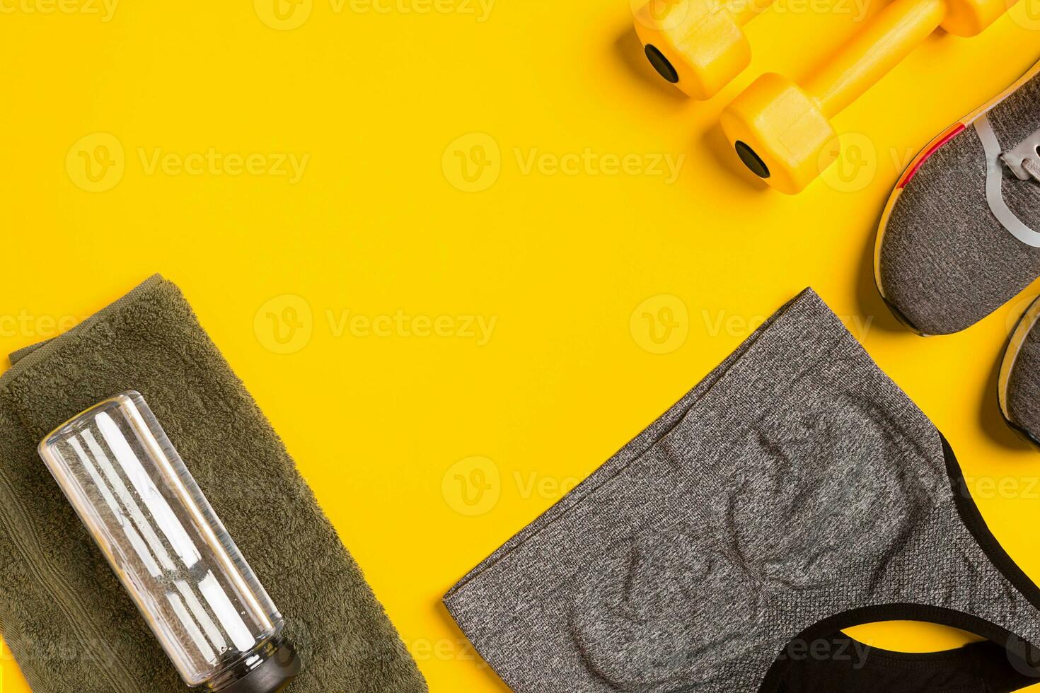 Fitness accessories on a yellow background. Sneakers, bottle of water, smart, towel and sport top. photo