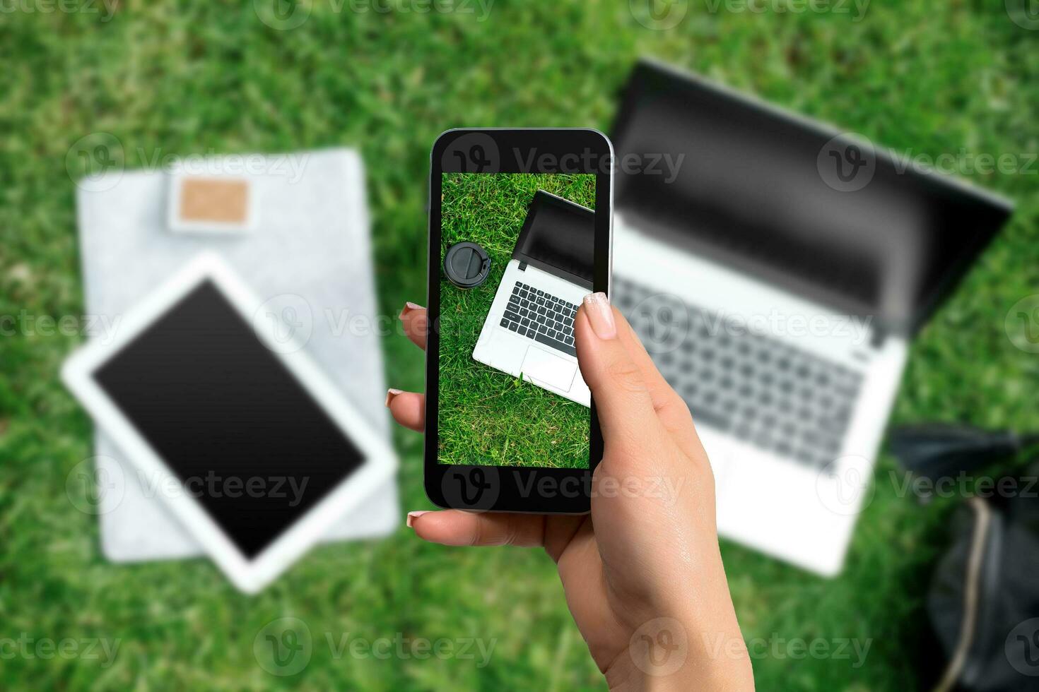 Female hand with a smartphone makes a photo laptop and coffee, outdoor office