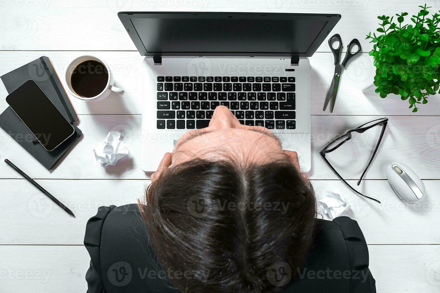 High angle view of an young brunette working at her office desk with documents and laptop. photo