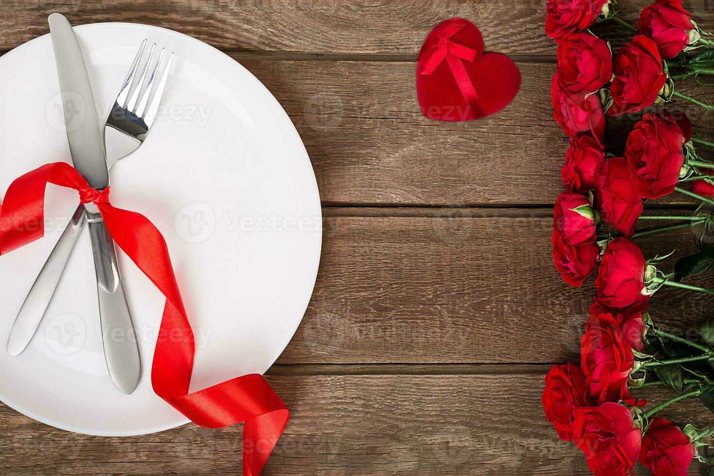 Valentines day table setting with plate, fork, knife, red heart, ribbon and roses. background photo