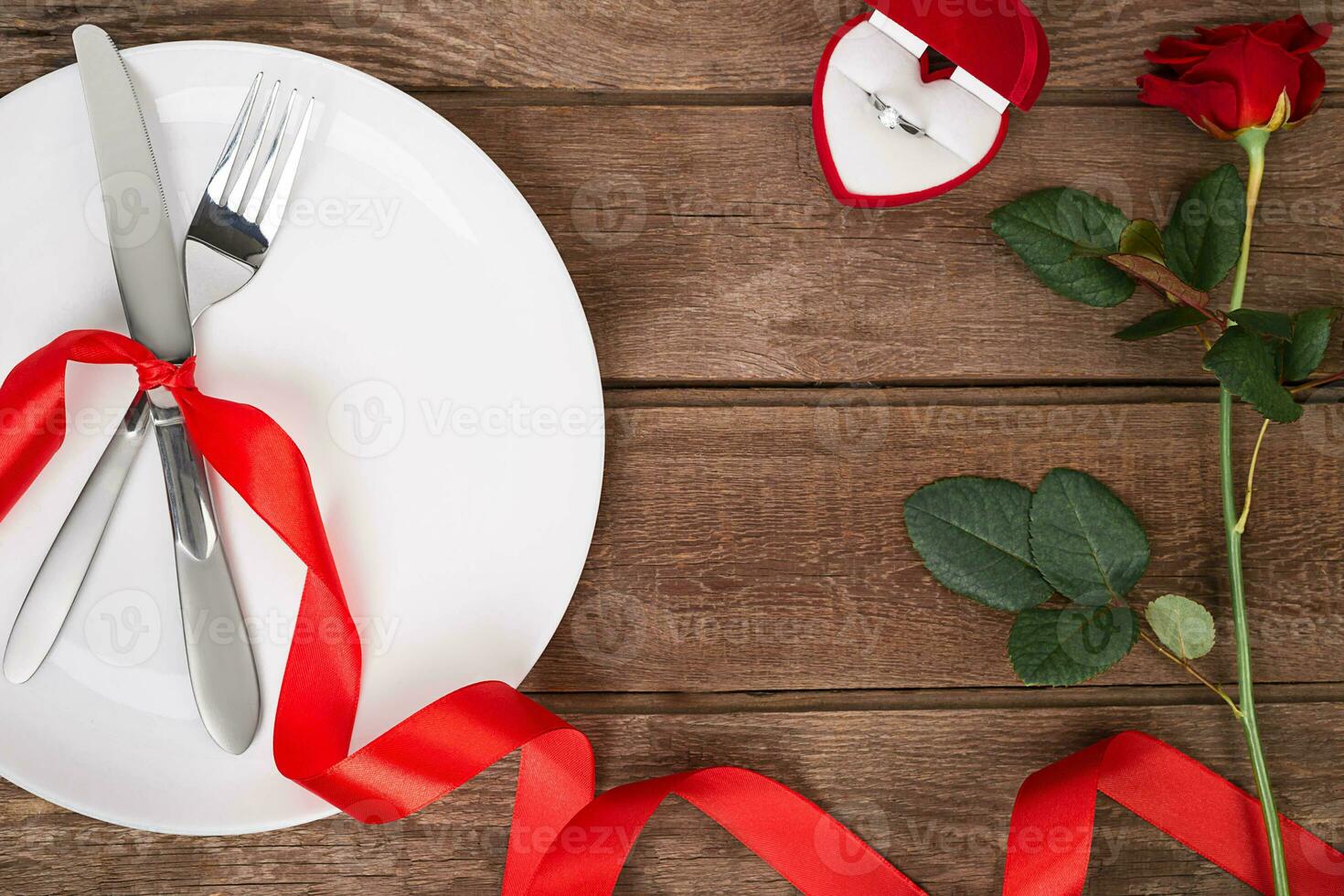 Valentines day table setting with plate, fork, knife, ring, ribbon and rose. background photo