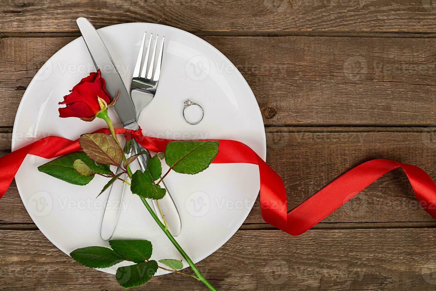 Valentines day table setting with plate, fork, knife, ring, ribbon and rose. background photo