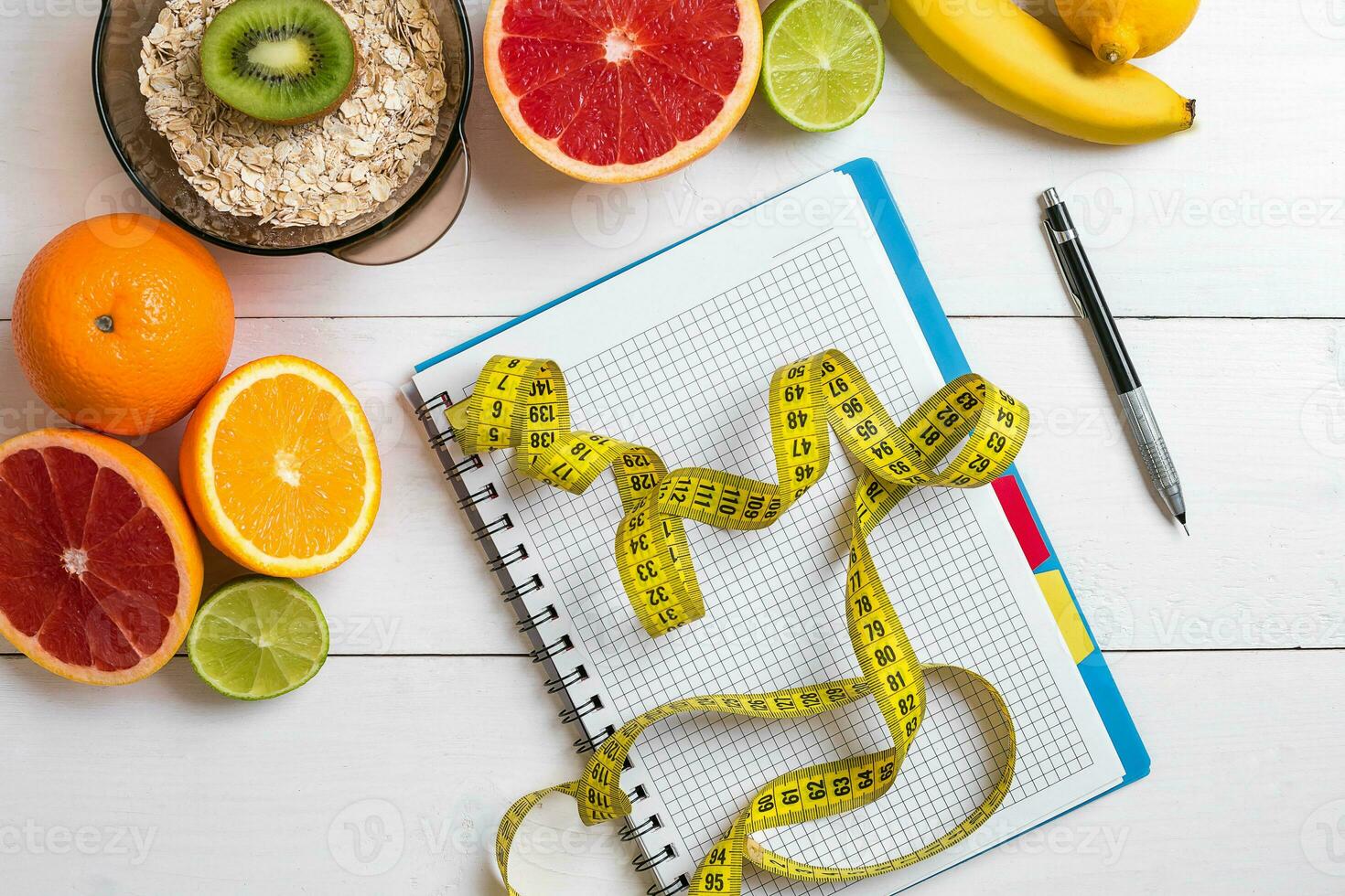 Healthy breakfast with oatmeal, fresh fruits and notebook on rustic wooden table. photo