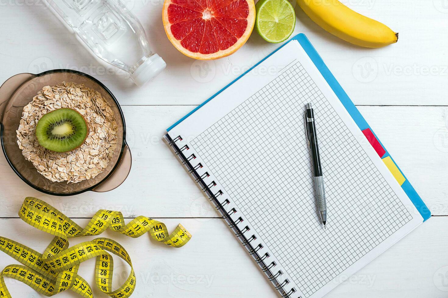 Fresh fruits with tape measure over white wooden background. Top view photo