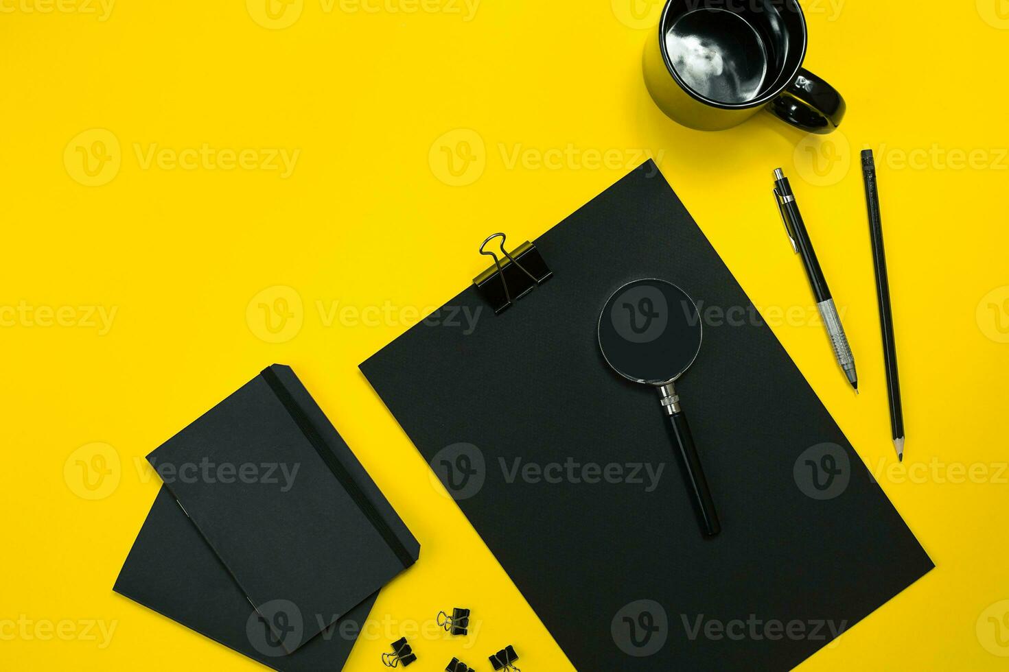 Flat lay display of business office gadgets with notepad, cup, pen, develop, glasses and etc. Top view. Black office objects on a yellow background photo