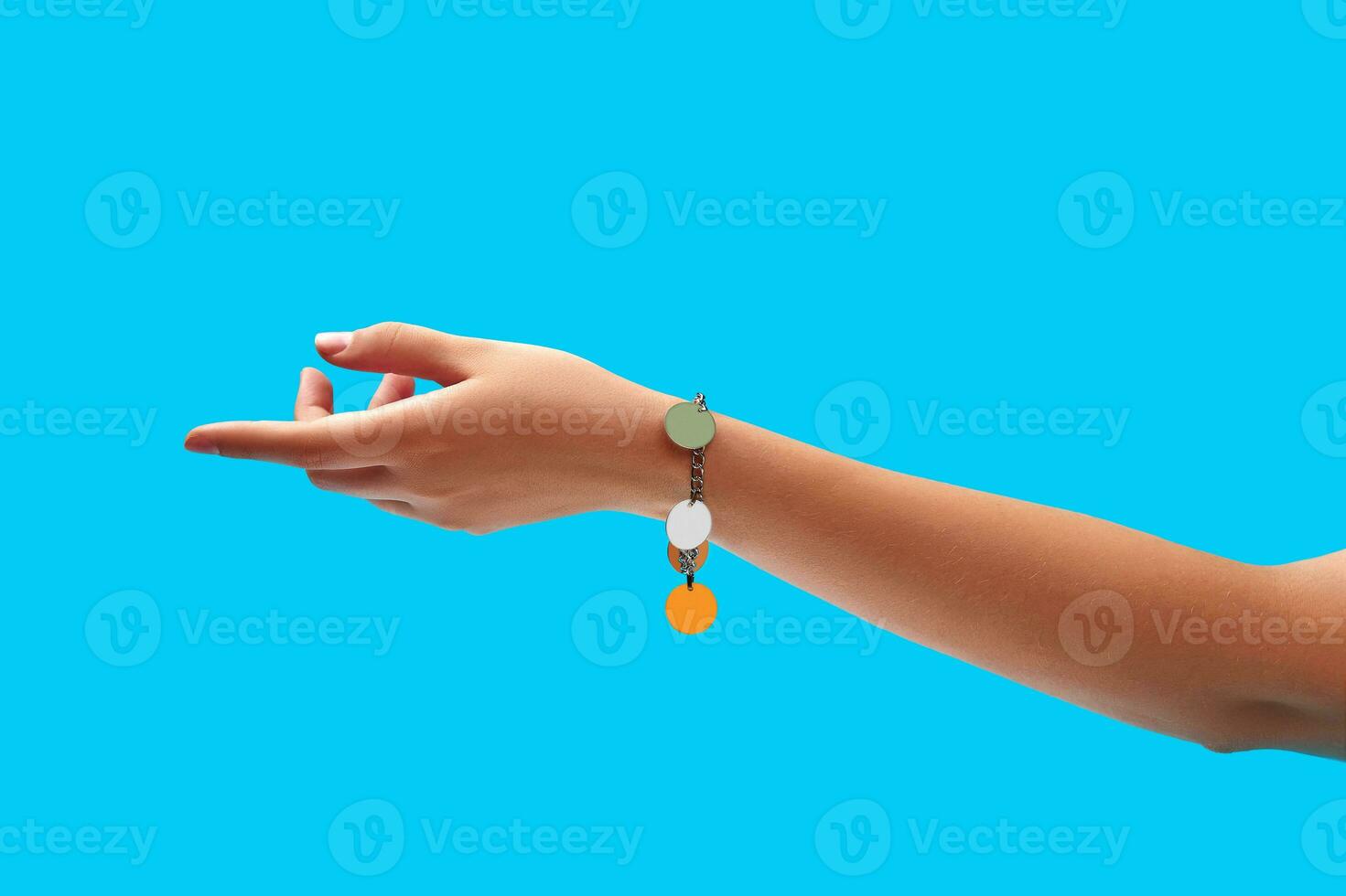 Hand of unknown young female in a shiny silver or platinum bracelet against blue studio background. Close up, copy space photo