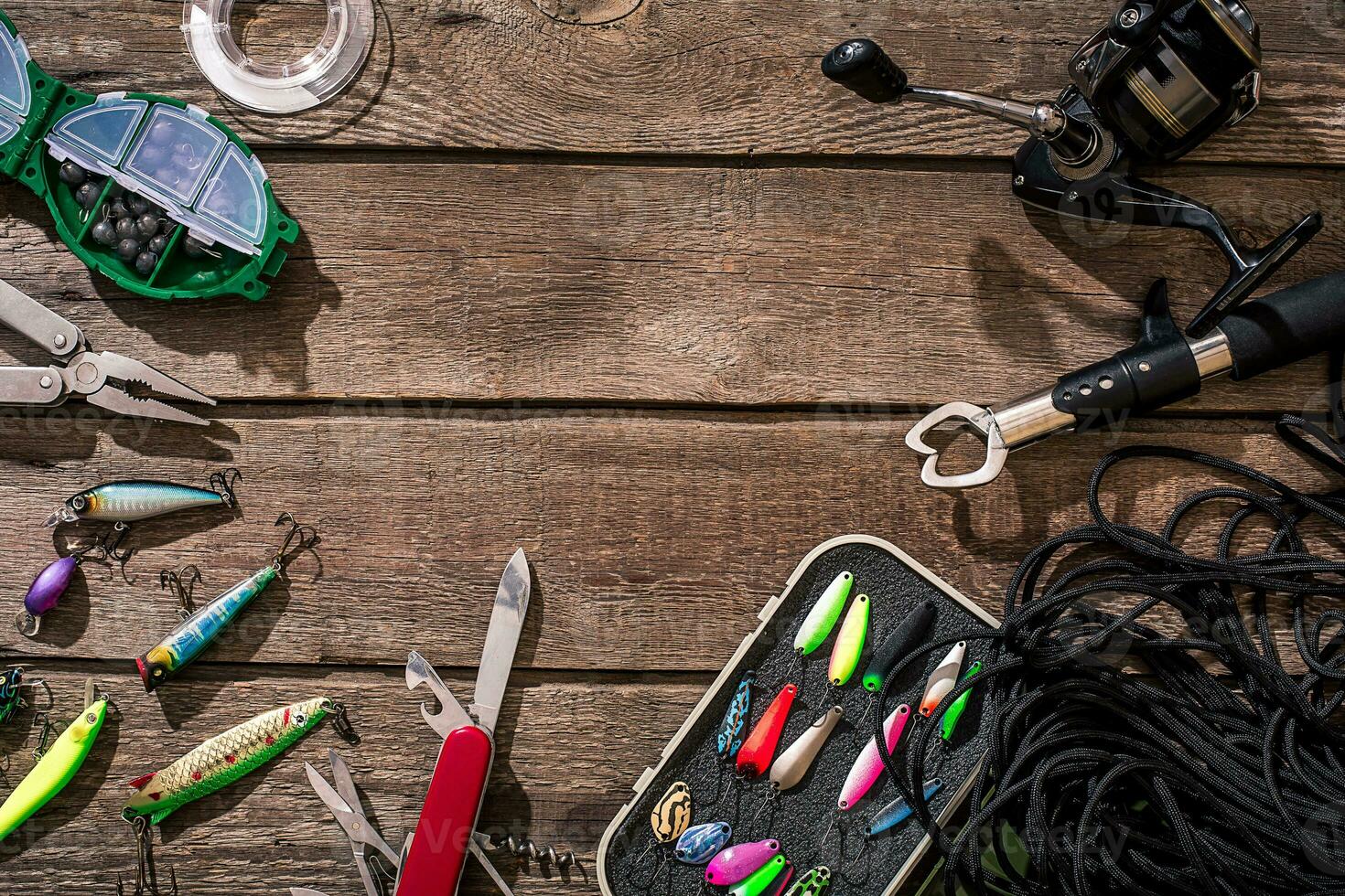 Fishing tackle - fishing spinning, fishing line, hooks and lures on wooden background. photo