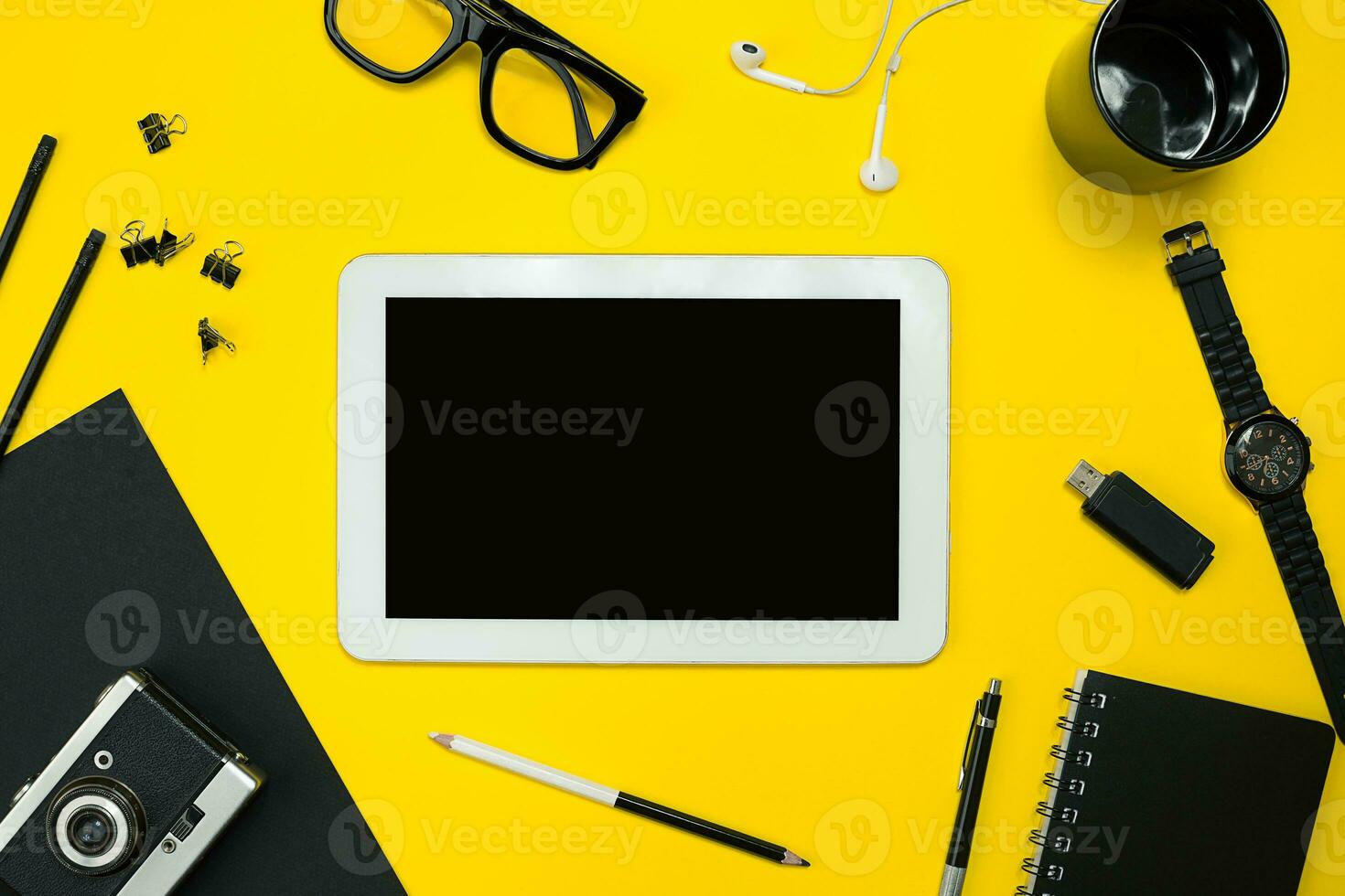 Flat lay display of business office gadgets with notepad, vintage camera, pen, develop, glasses and etc. Top view. Black office objects on a yellow background photo