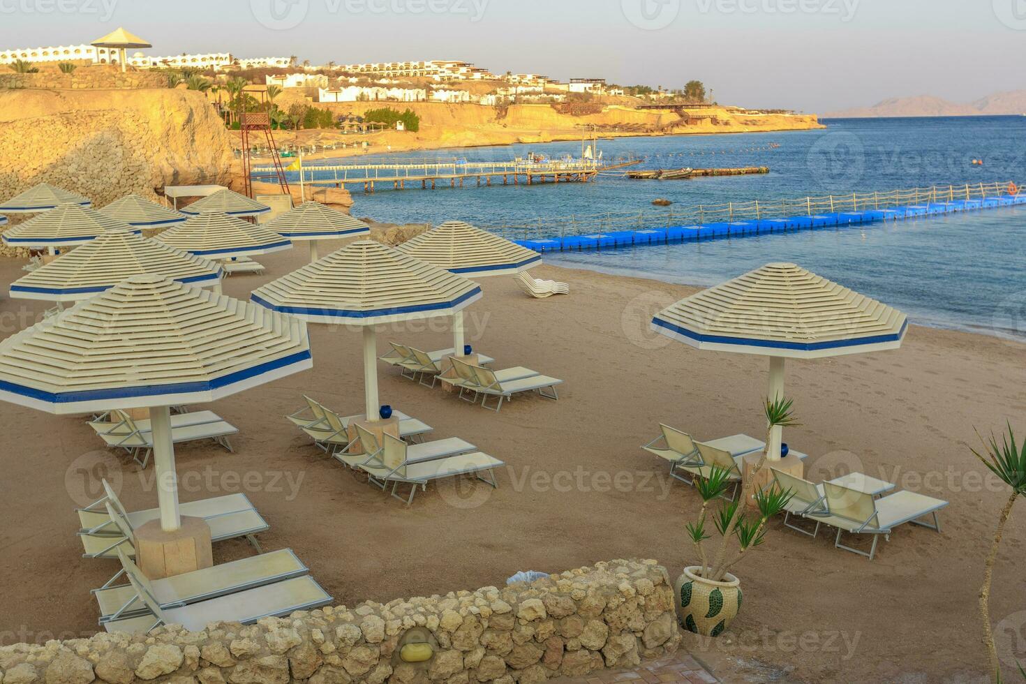 Beach with deck chairs and parasol during sunset photo