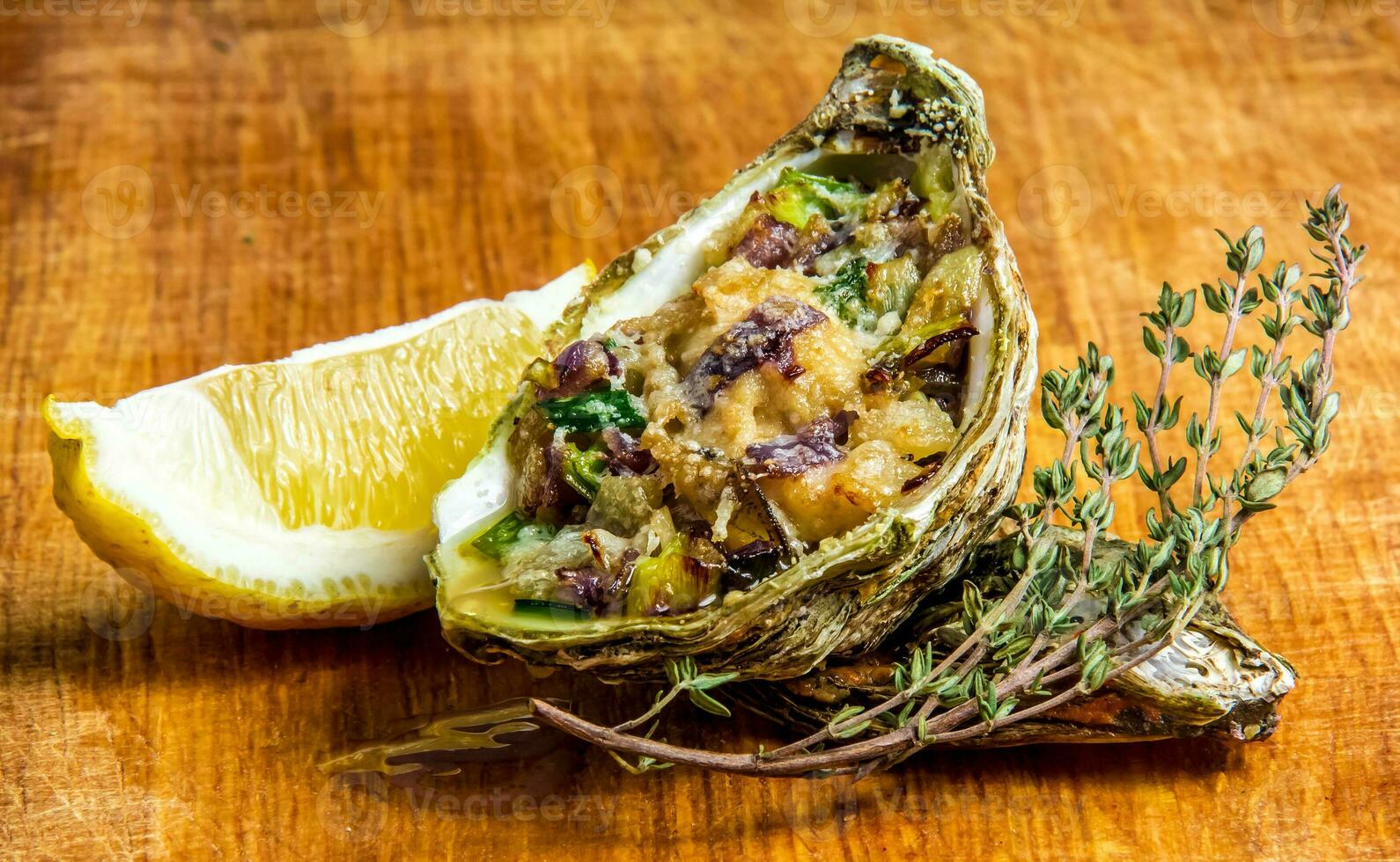 Baked oyster shell with cheese, served greens and lemon photo