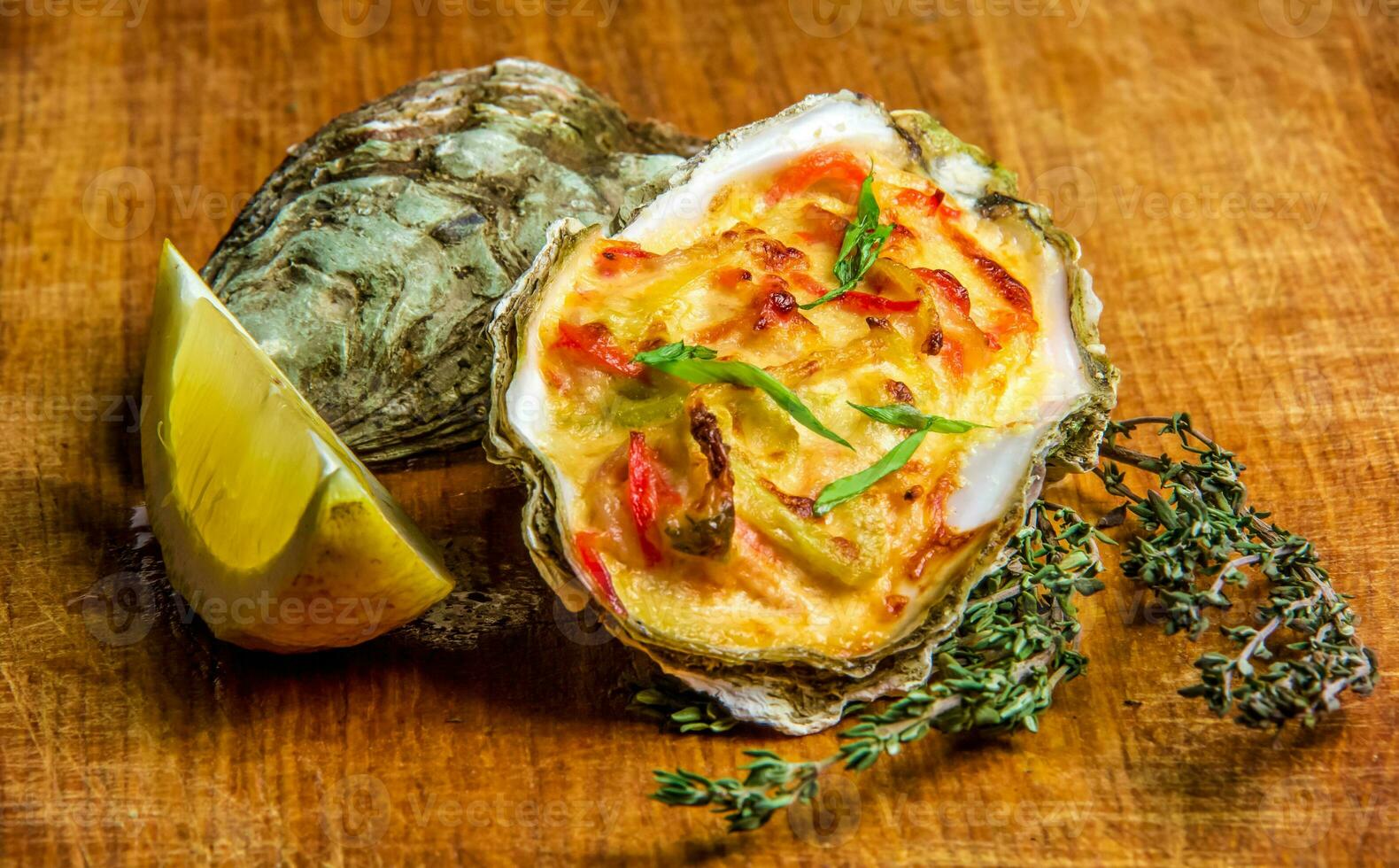 Baked oyster shell with cheese, served parsley and lemon photo