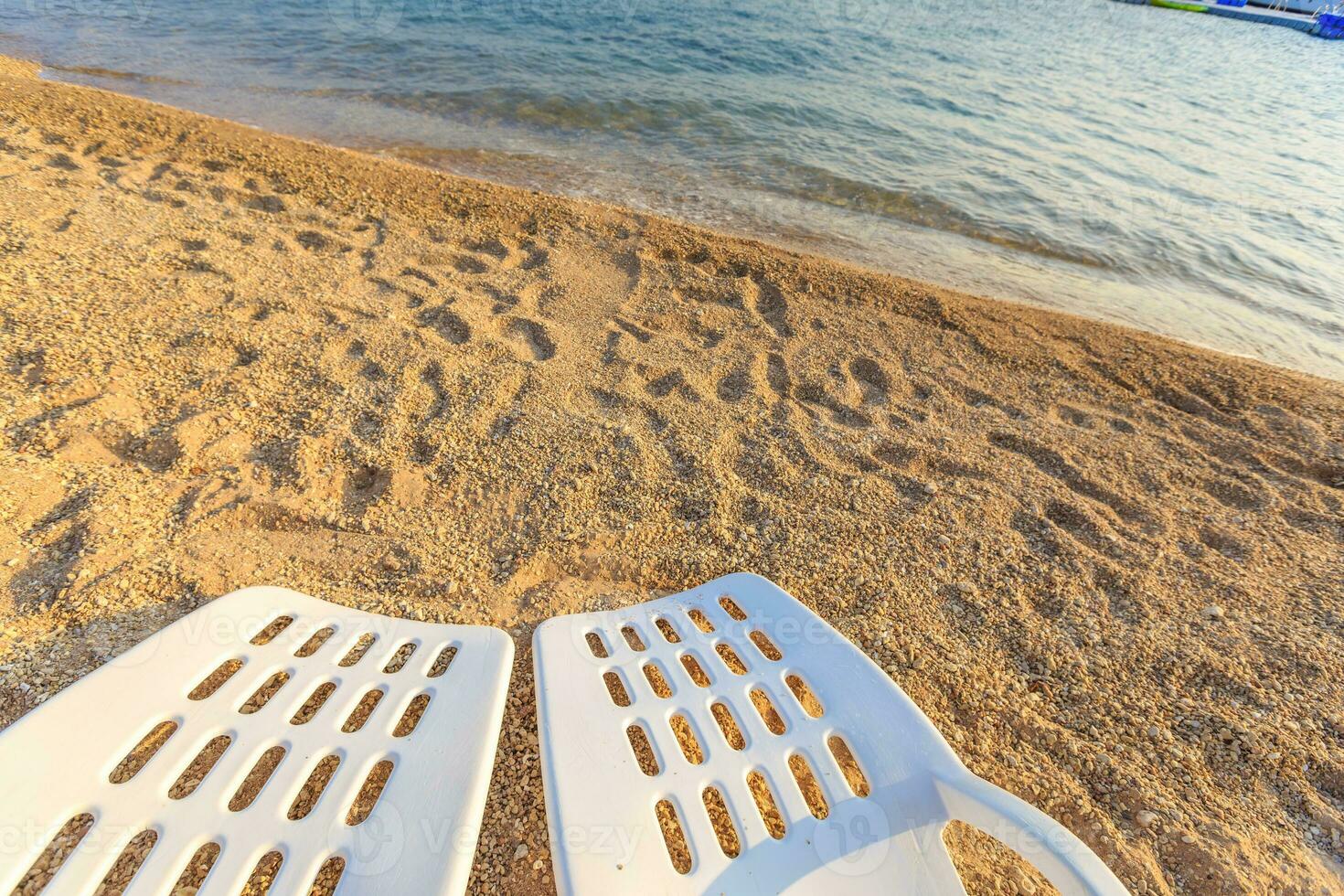 Two beachchairs on the sand near sea, closeup photo