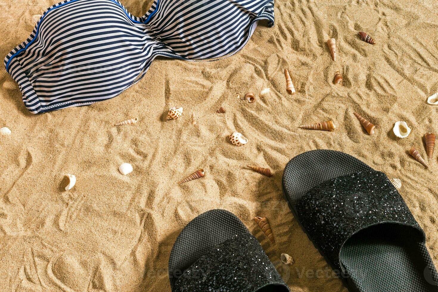 Summer bikini and accessories stylish beach set, Beach bikini summer outfit and sea sand as background, Top View, Concept photo