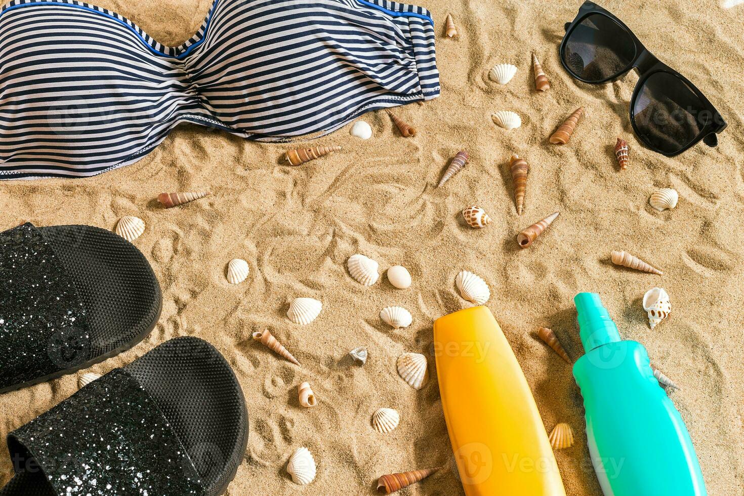 Summer bikini and accessories stylish beach set, Beach bikini summer outfit and sea sand as background, Top View, Concept photo