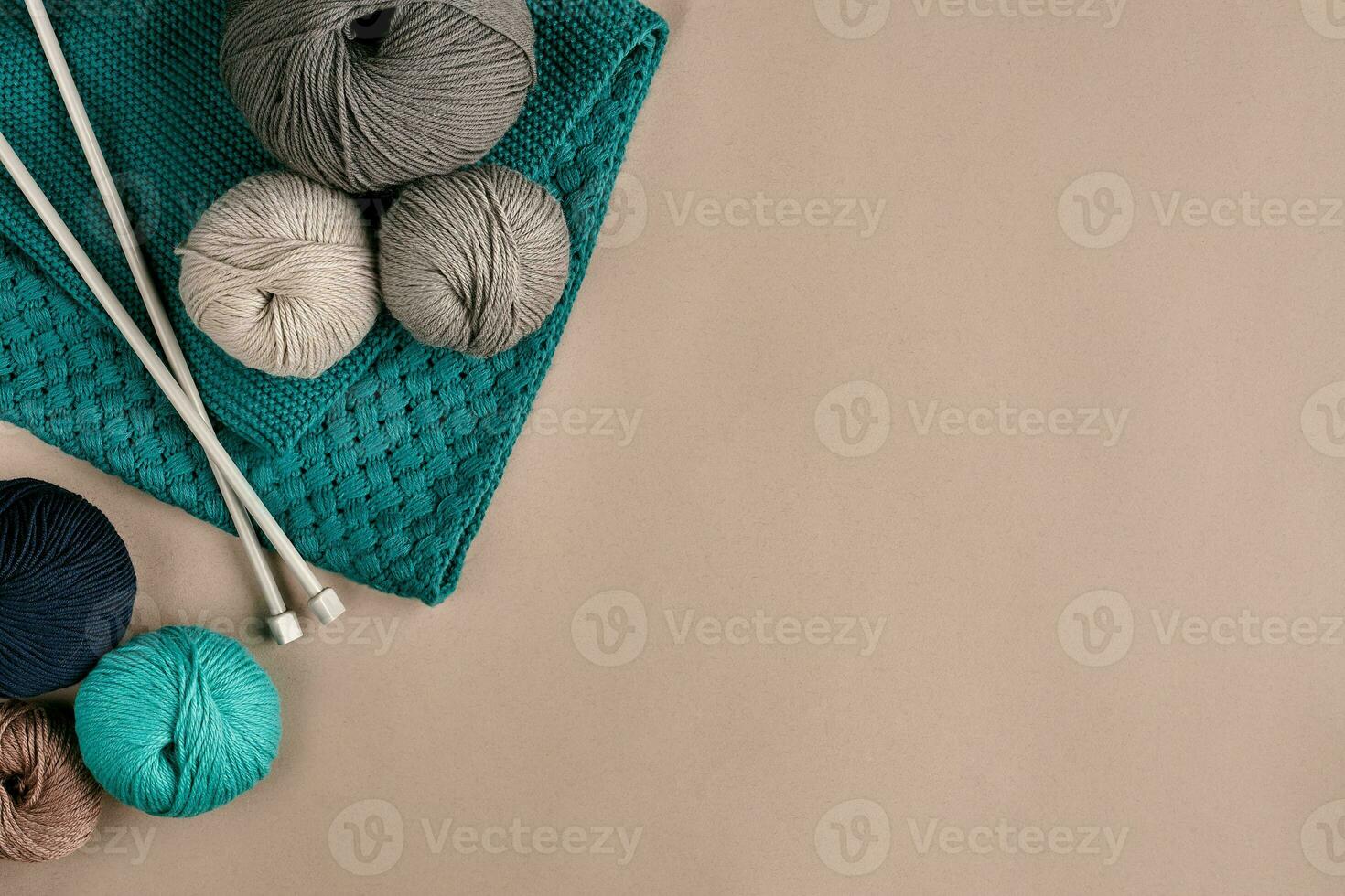 Grey and turquoise knitting wool and knitting needles on beige background. Top view. Copy space photo