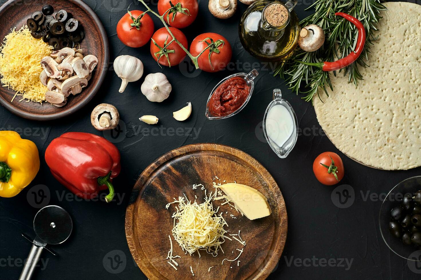 Cheese, different vegetables on black table. Ingredients for traditional italian pizza. photo