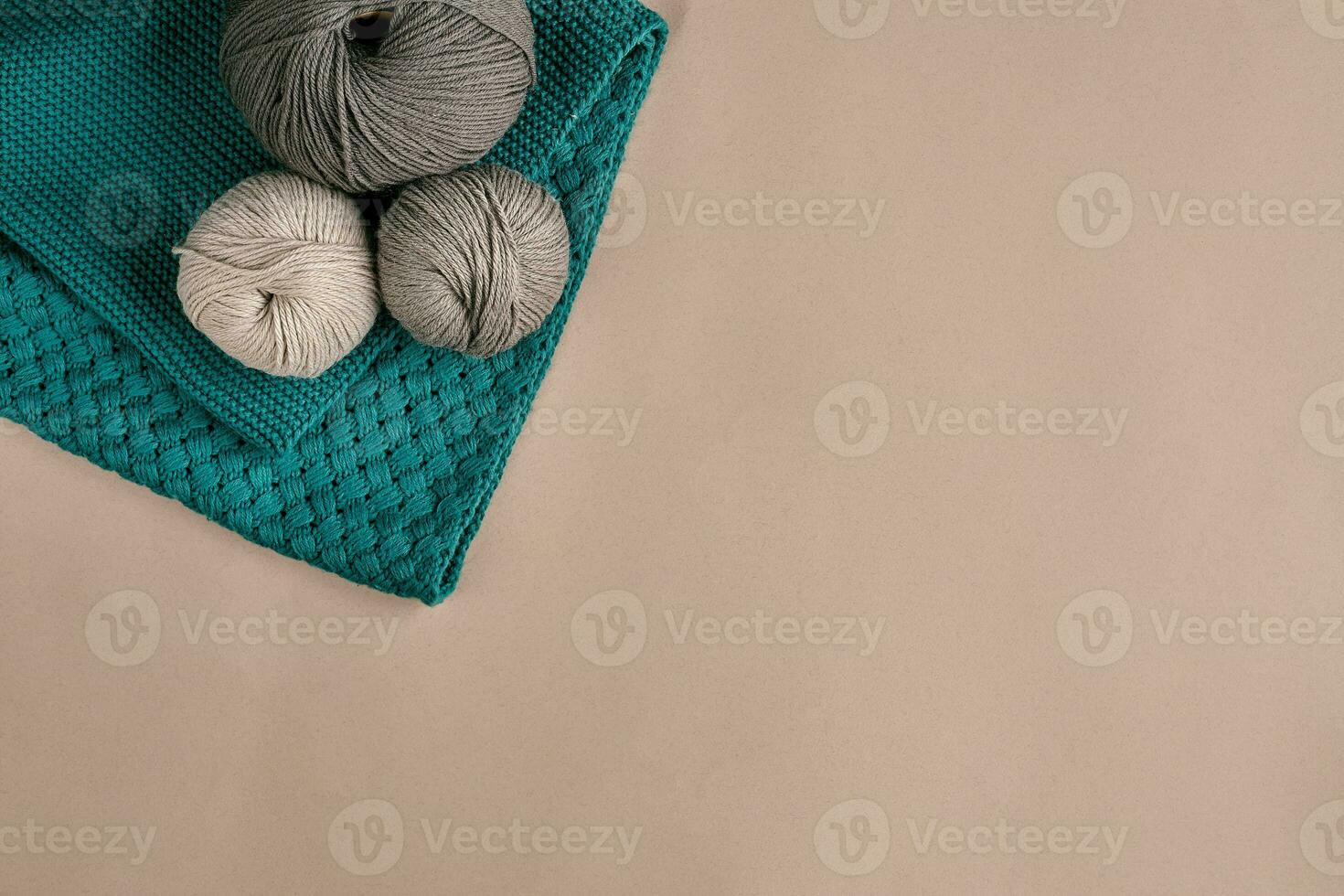 Grey and turquoise knitting wool and knitting needles on beige background. Top view. Copy space photo