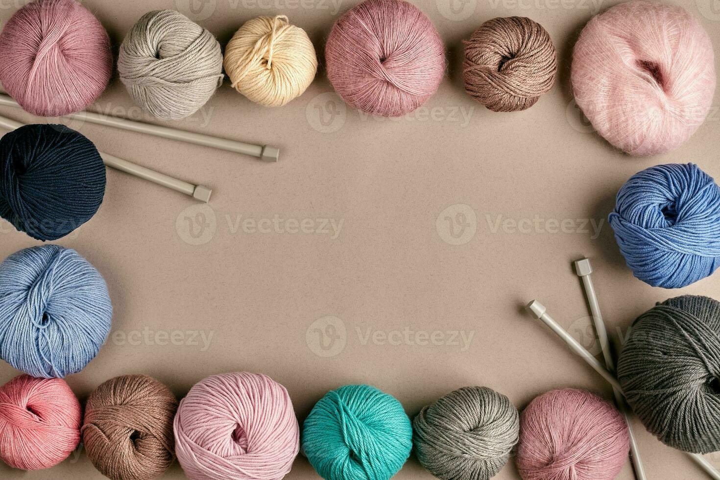 A group of colored balls of yarn and knitting needles on a beige background photo