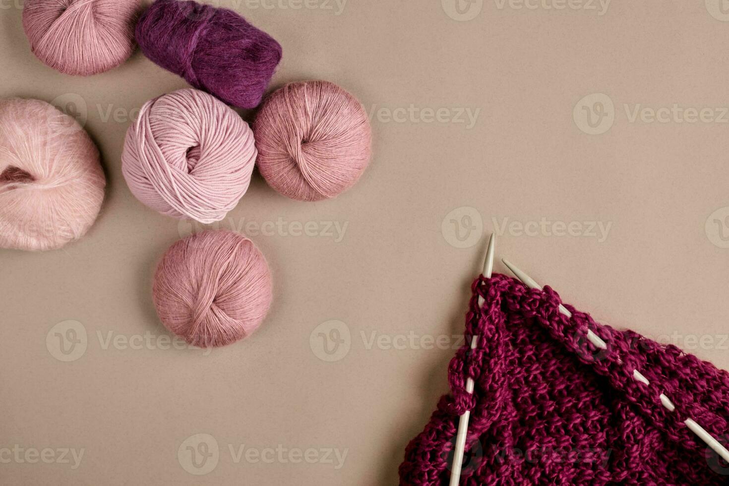 Balls of merino wool yarn, knitting on knitting needles on a beige surface. Top view photo