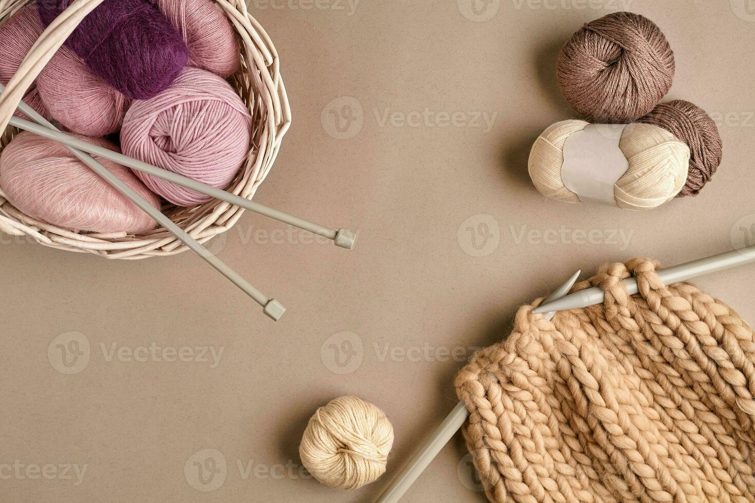 Balls of merino wool yarn, knitting on knitting needles on a beige surface. Top view photo