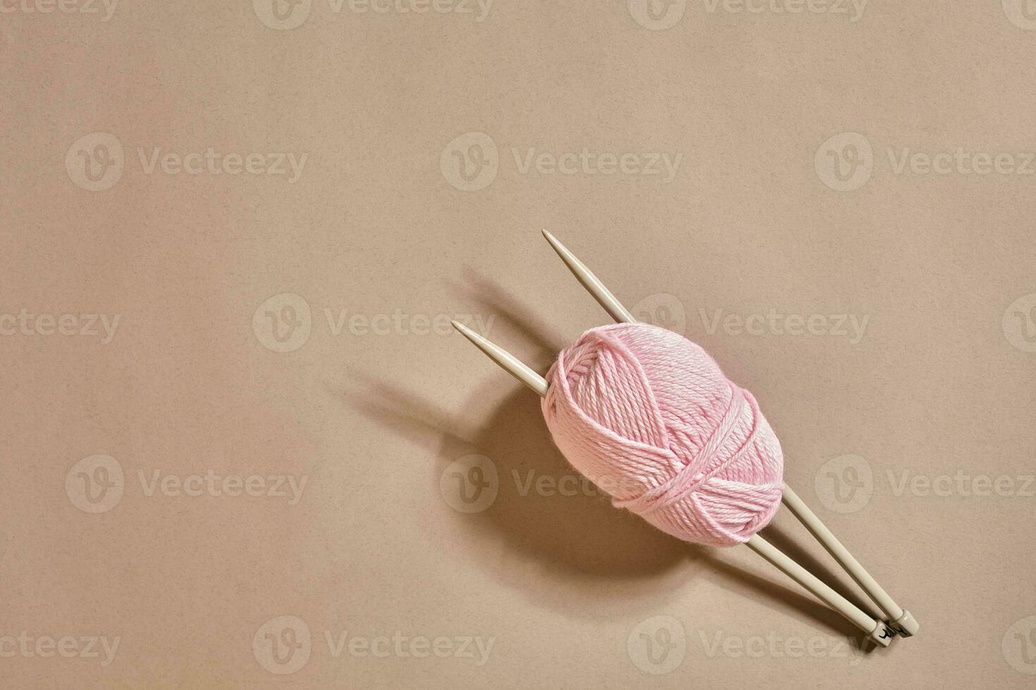 Pink knitting yarn ball and knitting needles top view photo