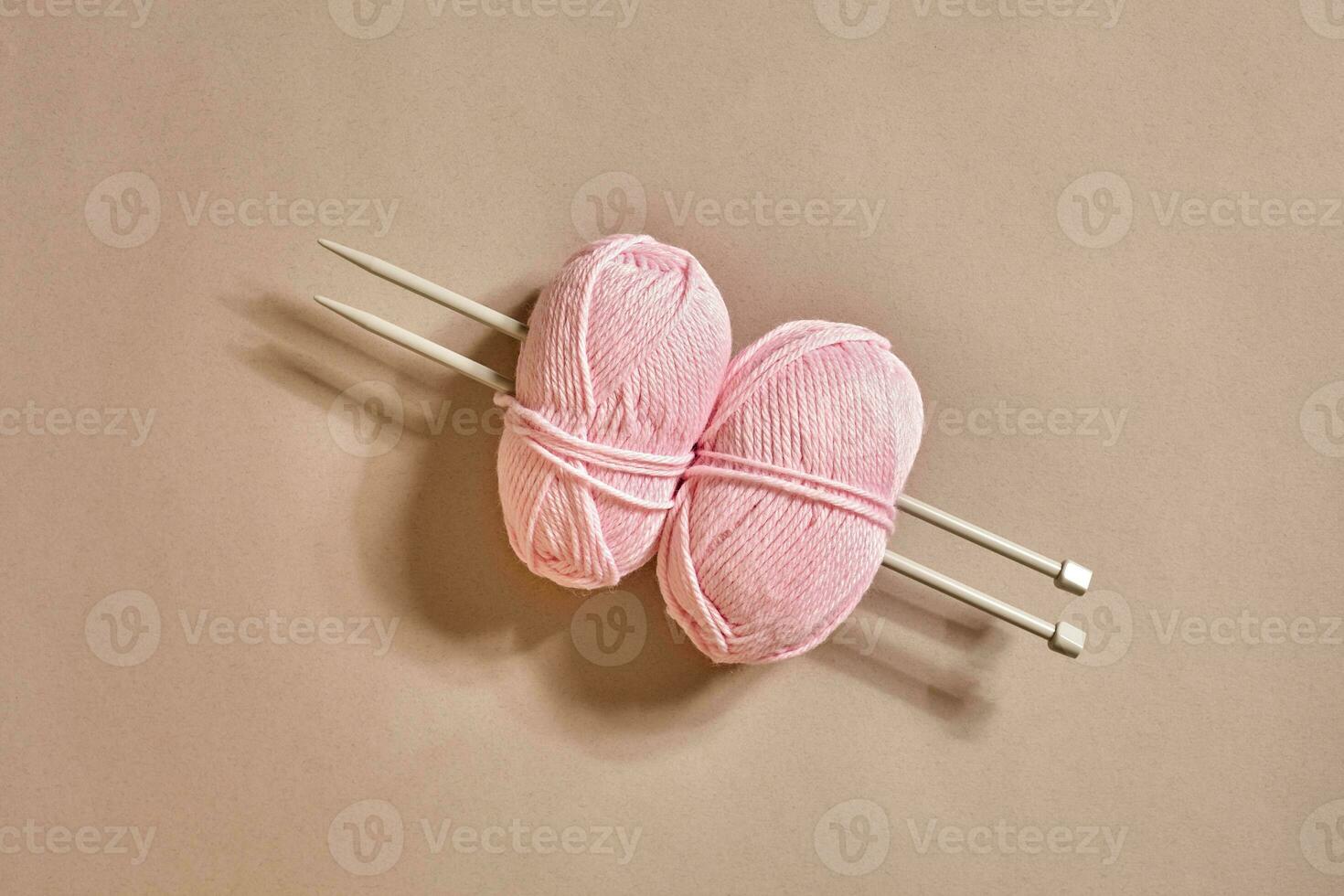 Two pink knitting yarn balls and knitting needles top view photo
