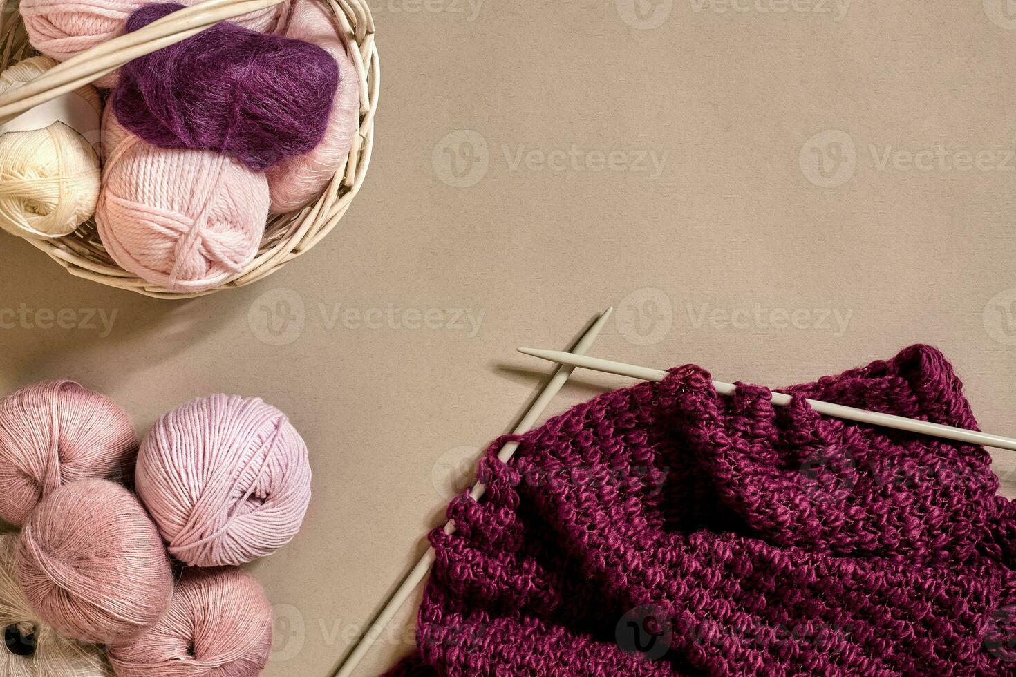 Balls of merino wool yarn, knitting on knitting needles on a beige surface. Top view photo