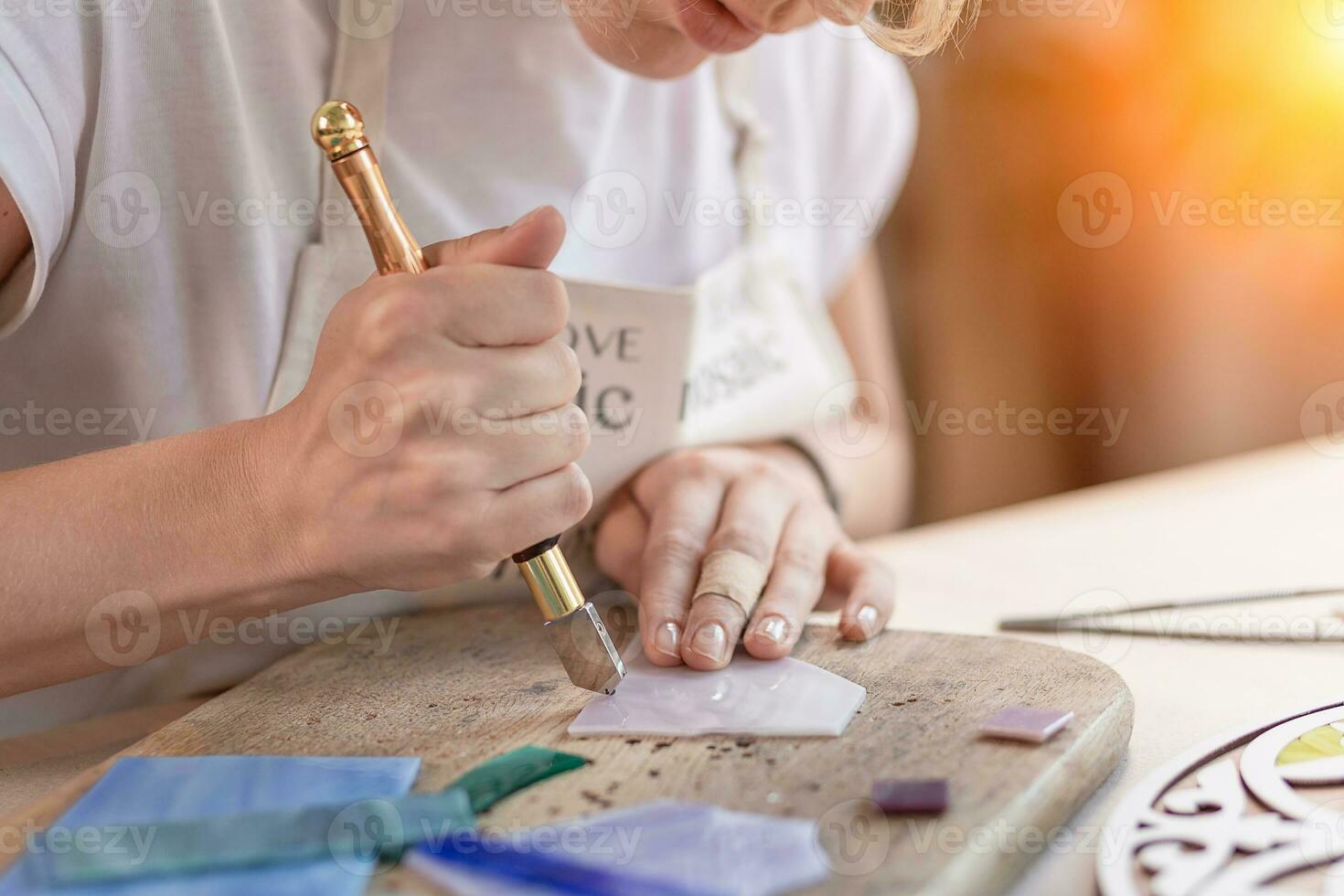 artista corte hojas de manchado vaso dentro pequeño mosaico cuadrícula. de cerca foto