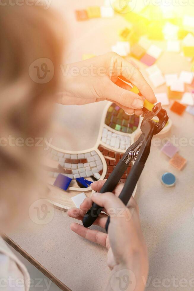 Hands of master working on new modern colorful mosaic. Close-up photo
