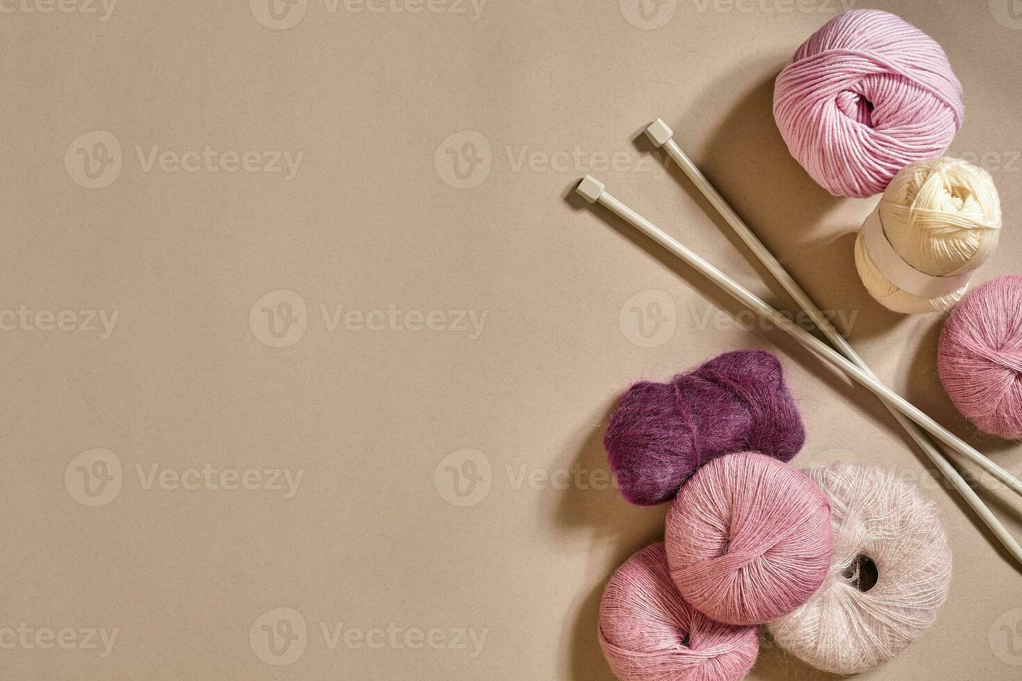 A group of colored balls of yarn and knitting needles on a beige background photo
