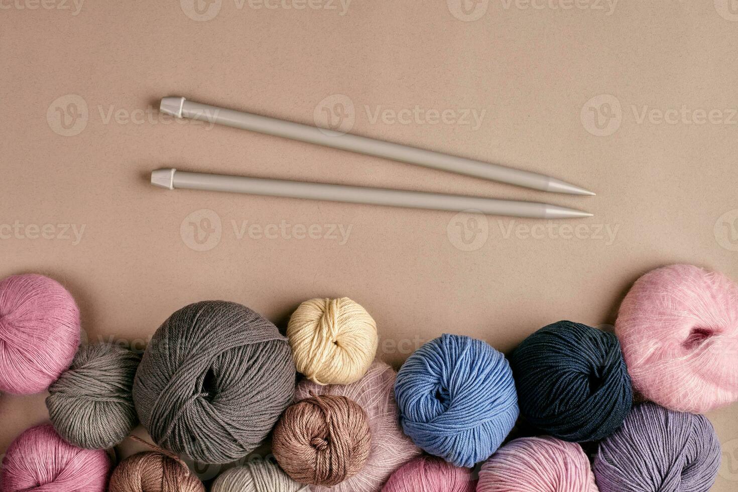 A group of colored balls of yarn and knitting needles on a beige background photo