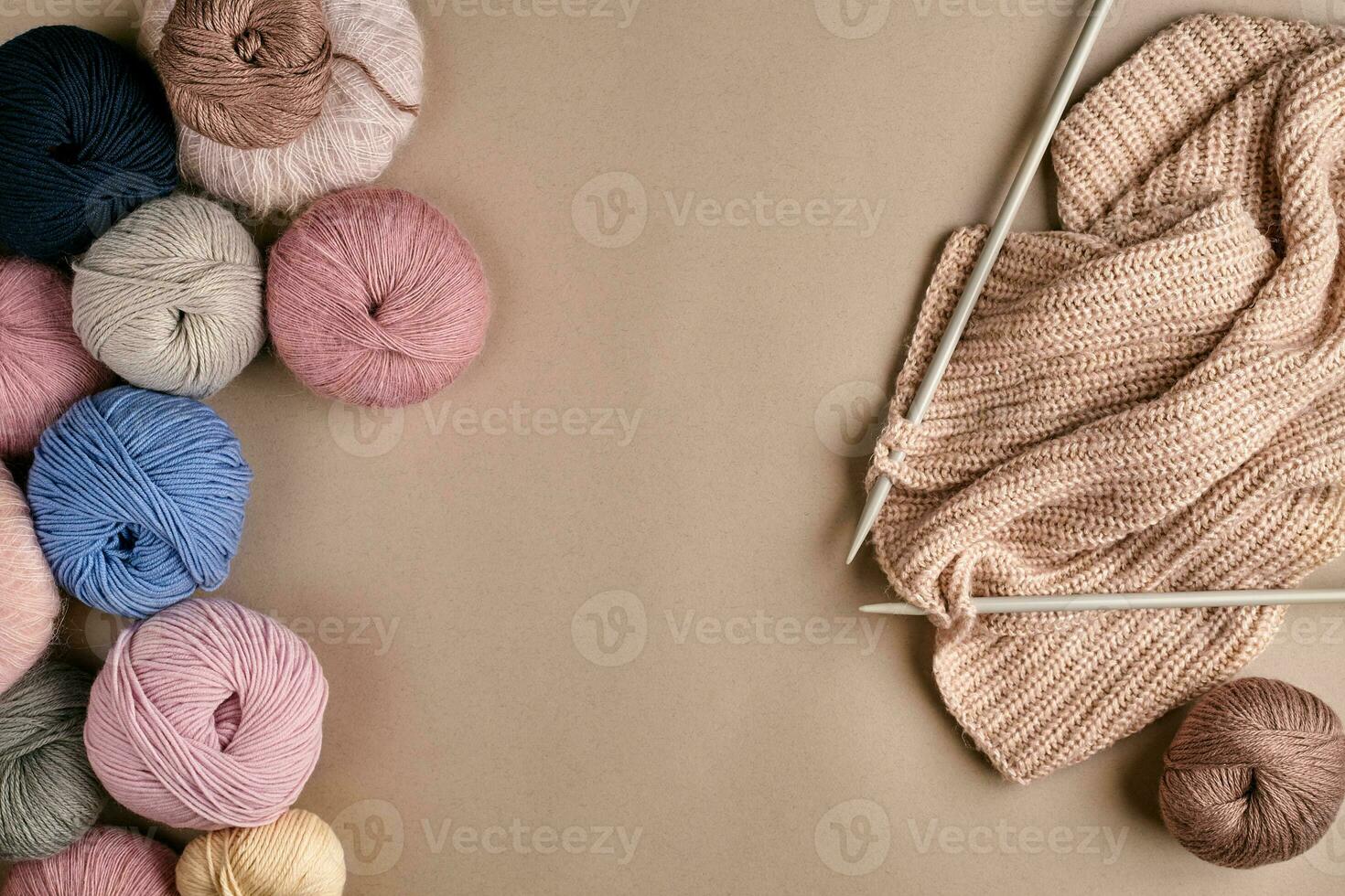 Set of colorful wool yarn and knitting on knitting needles on beige background. Top view photo