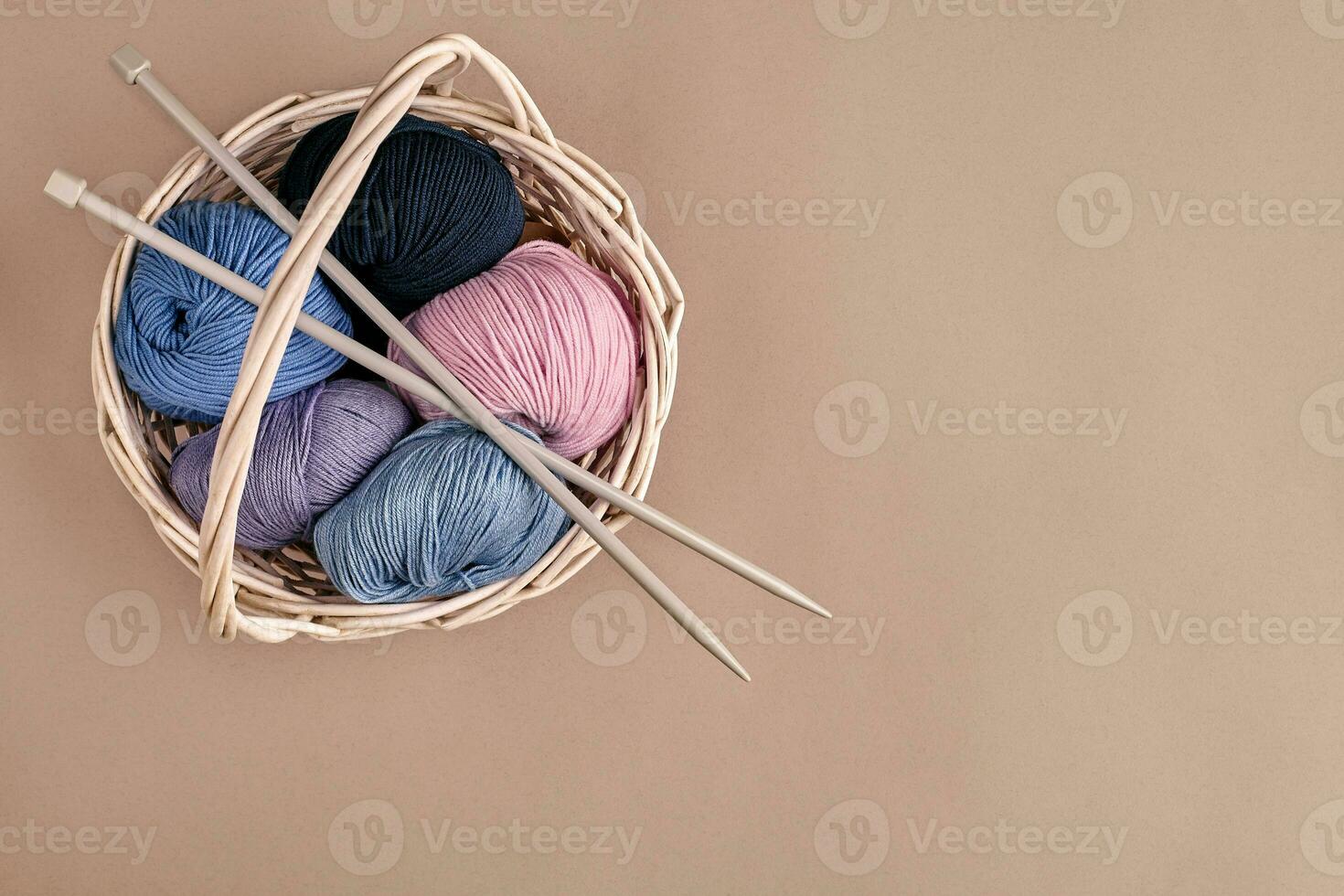 Different colored yarn in basket with knitting needles. Top view photo