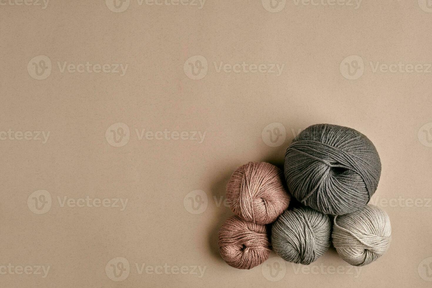 Grey and brown knitting wool and knitting needles on beige background. Top view. Copy space photo
