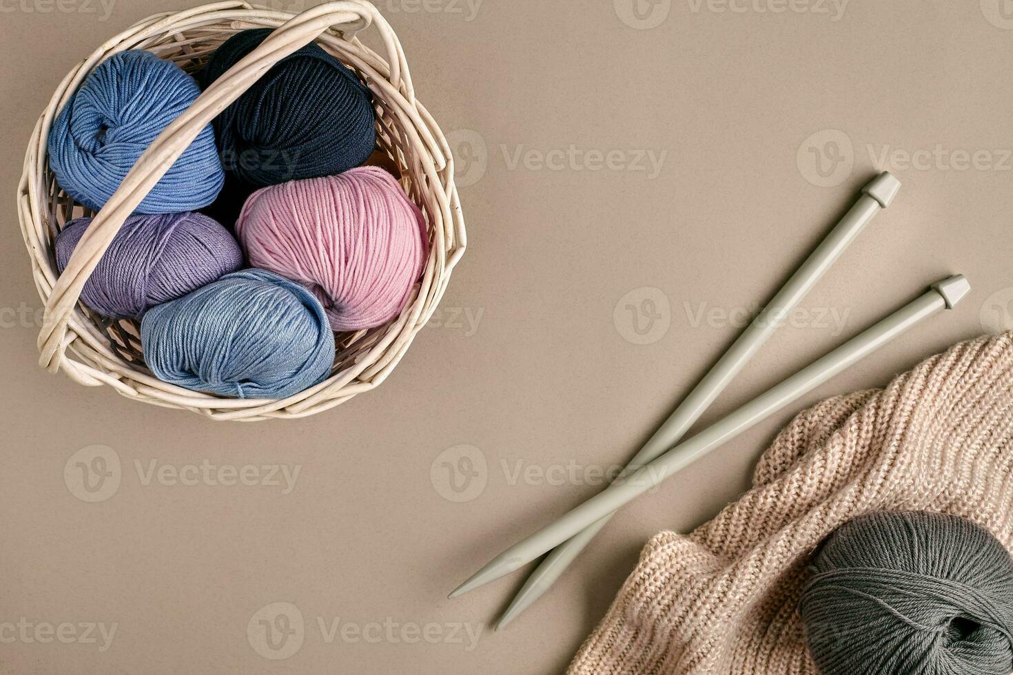 Different colored yarn in basket with knitting needles. Top view photo