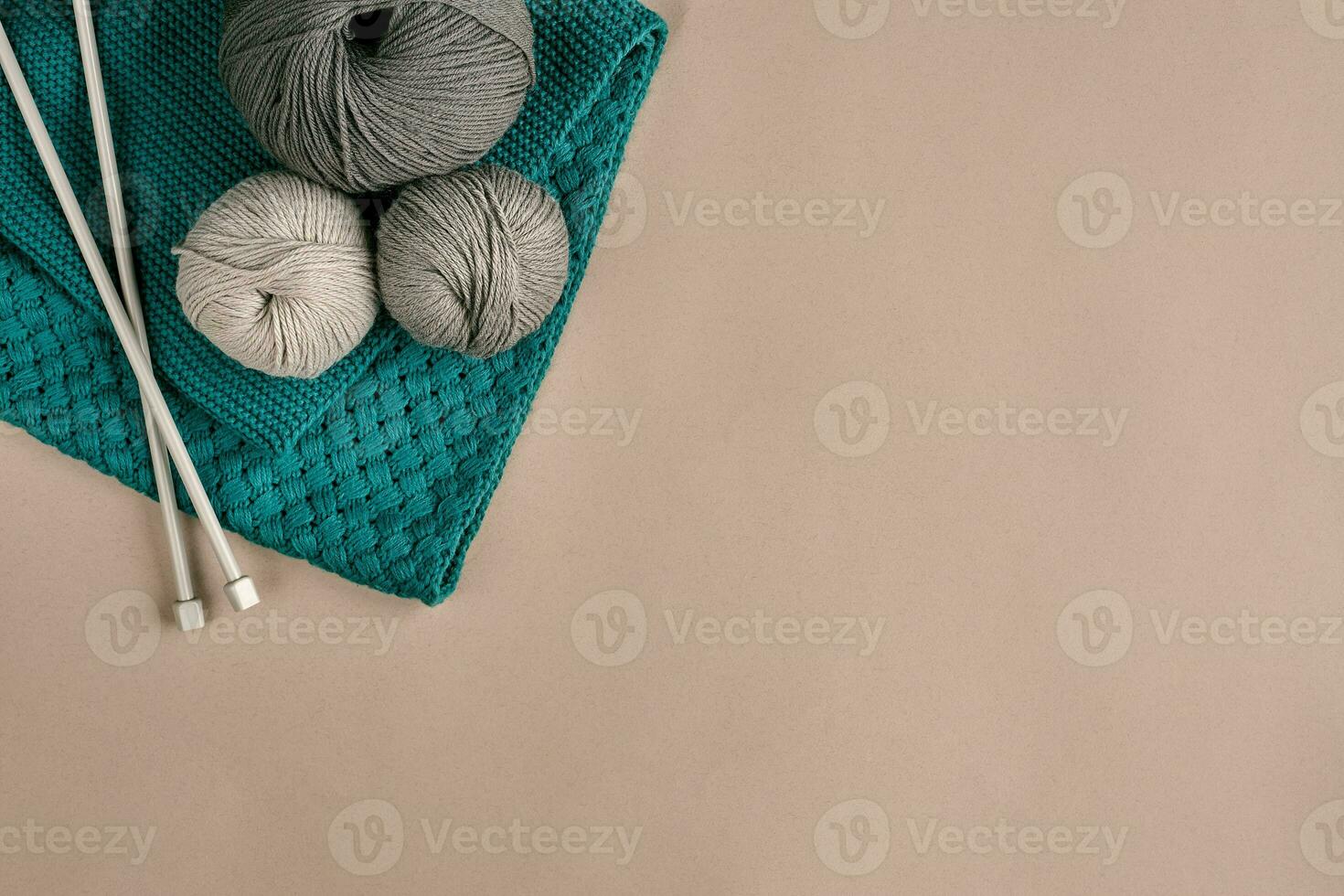 Grey and turquoise knitting wool and knitting needles on beige background. Top view. Copy space photo