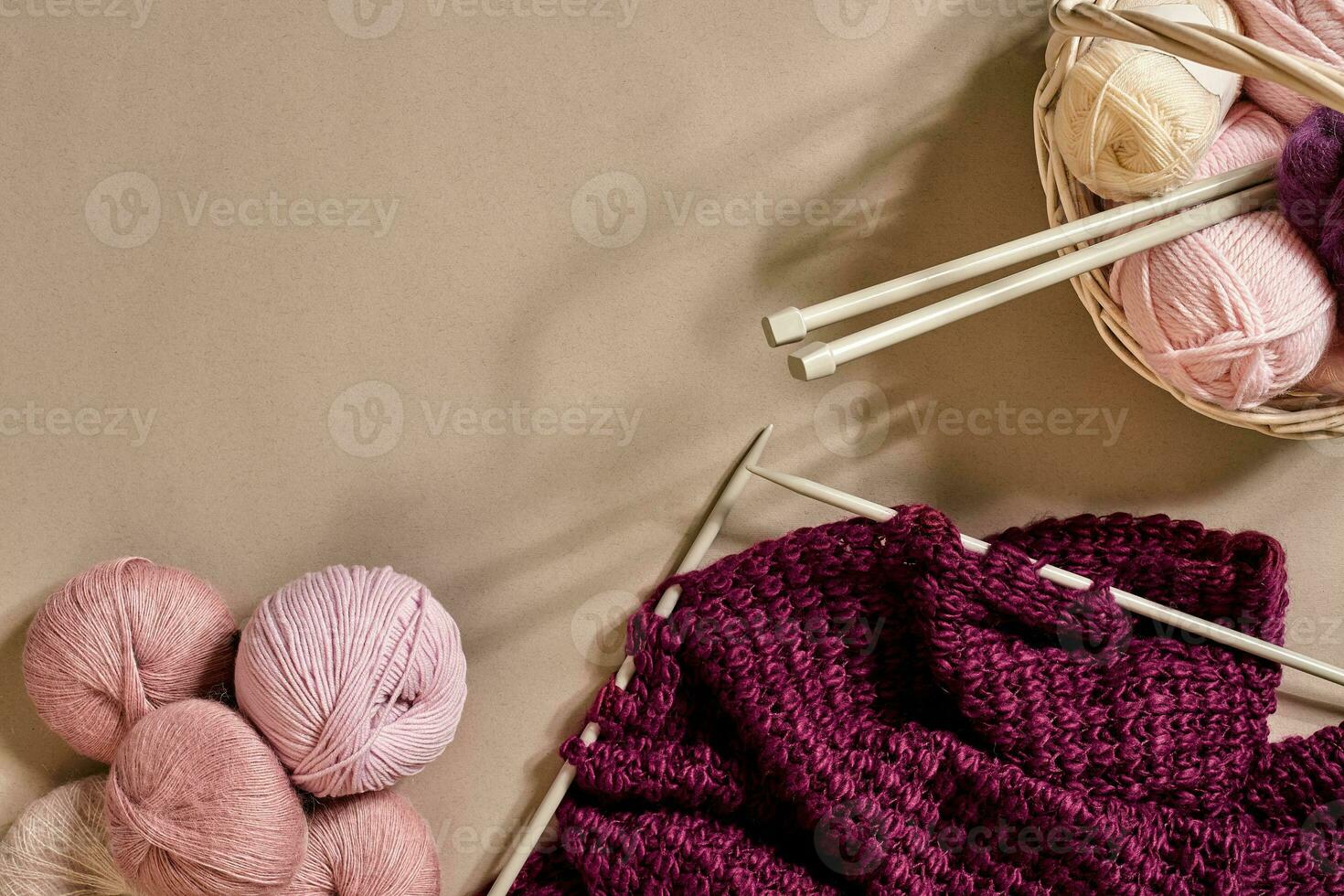 Balls of merino wool yarn, knitting on knitting needles on a beige surface. Top view photo