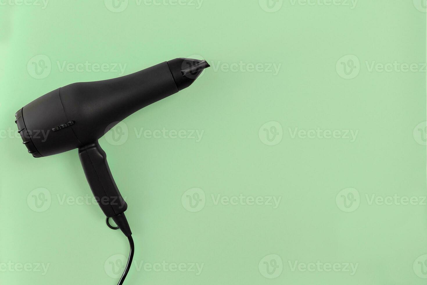 Black hair dryer on green paper background photo