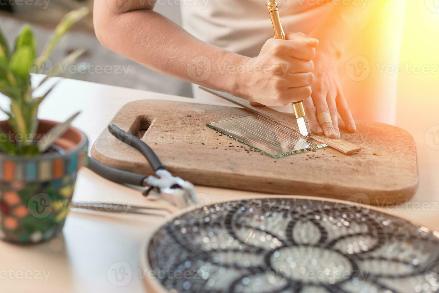 Artist cutting sheets of stained glass into small mosaic squares. Close-up photo