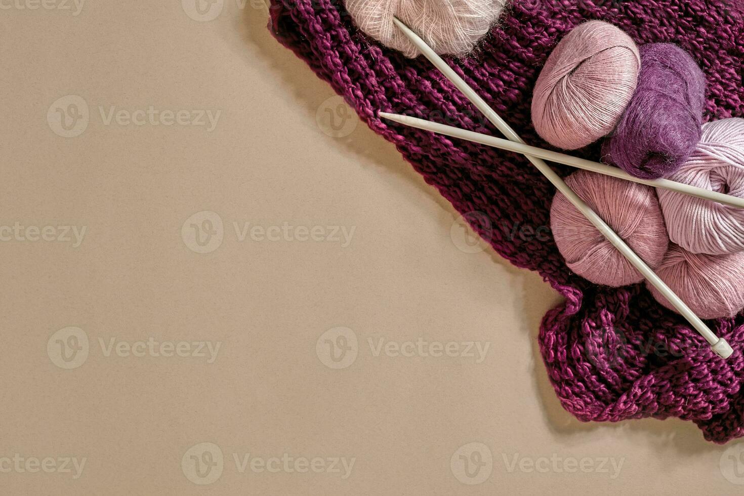 A group of colored balls of yarn and knitting needles on a beige background photo