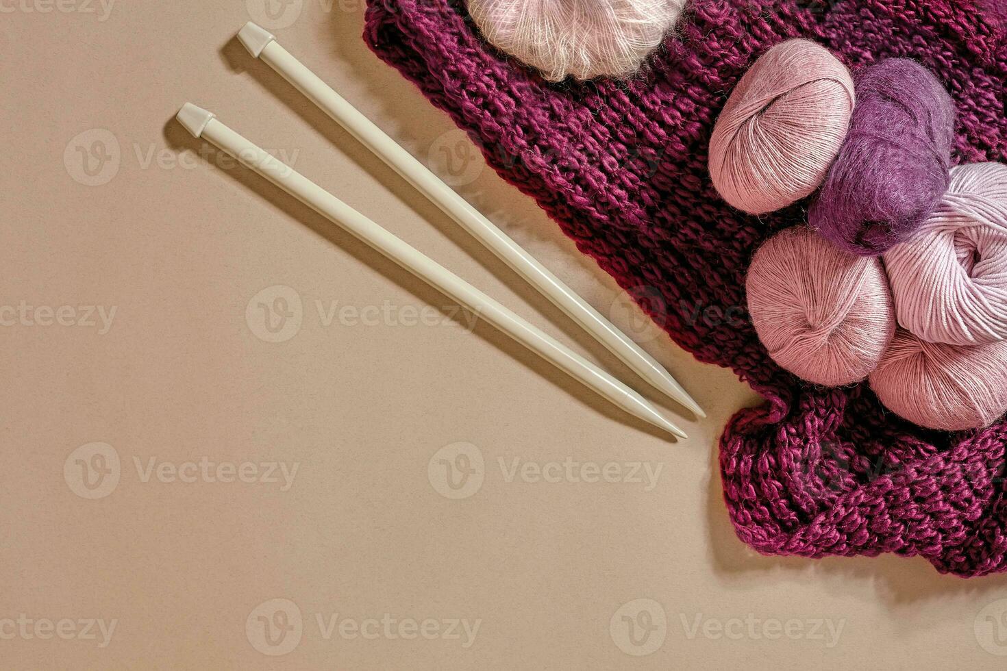A group of colored balls of yarn and knitting needles on a beige background photo