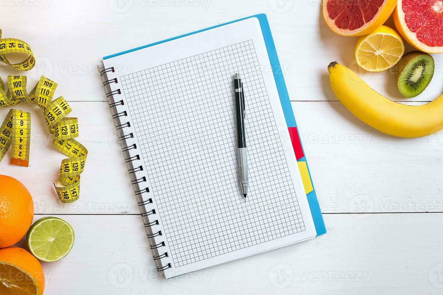 Fresh fruits with tape measure over white wooden background. Top view photo