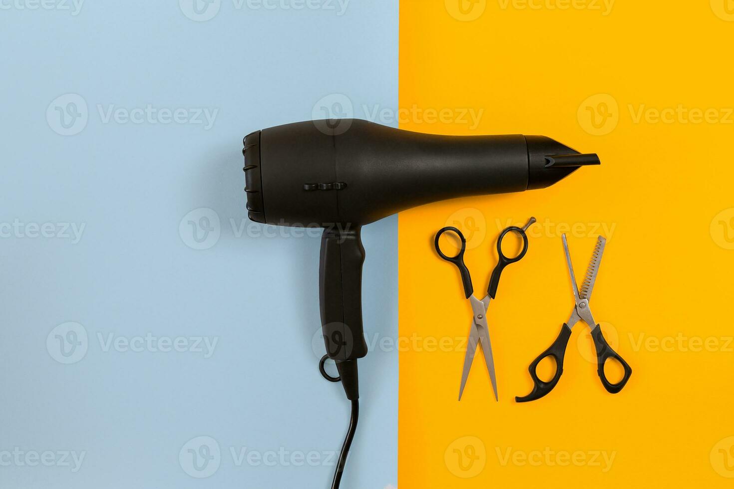Styling hair with scissors, dryer and tools in barbershop on blue and yellow paper background top view mock-up photo