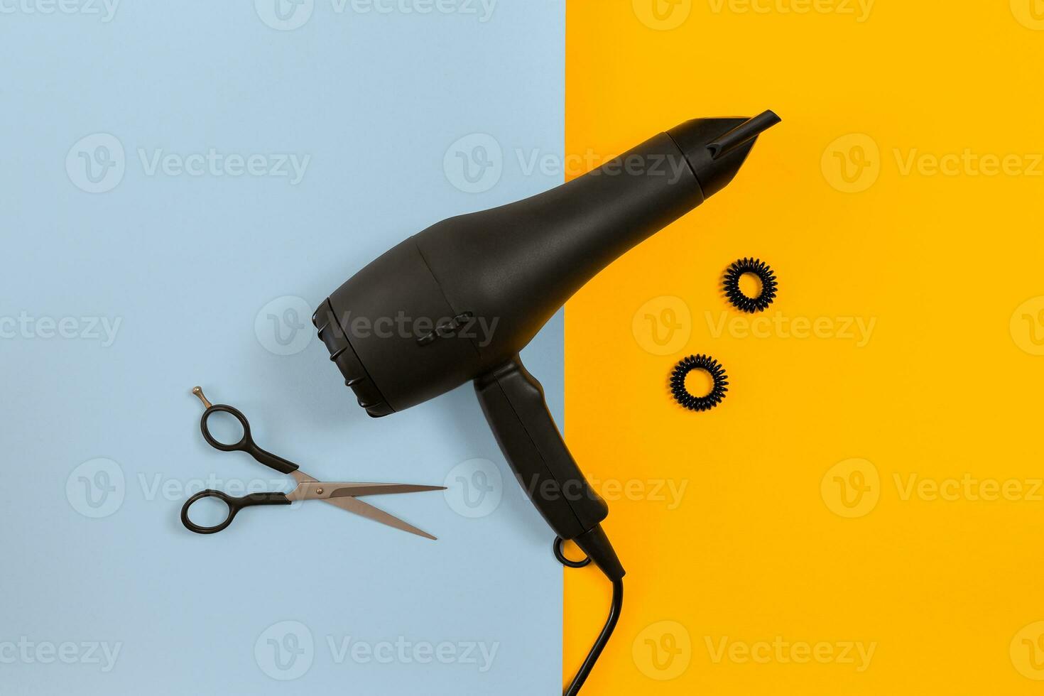 Styling hair with scissors, dryer and tools in barbershop on blue and yellow paper background top view mock-up photo
